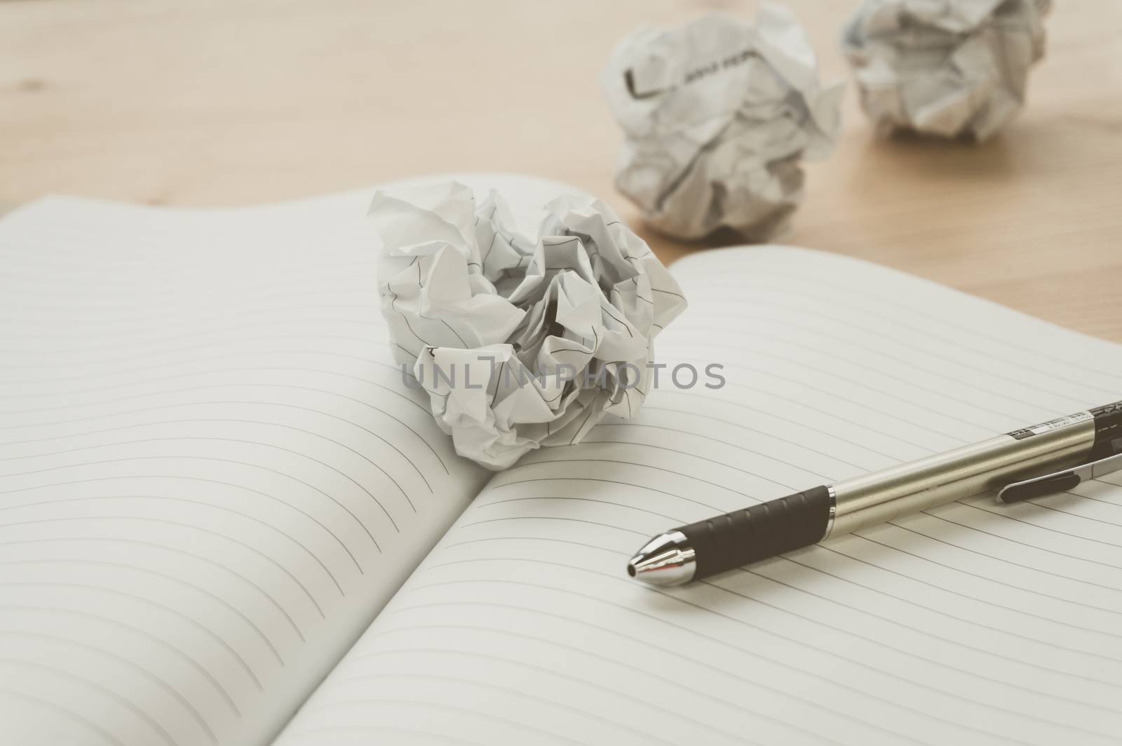 Crumpled paper balls with pen and notebook on wood desk.vintage effect style picture