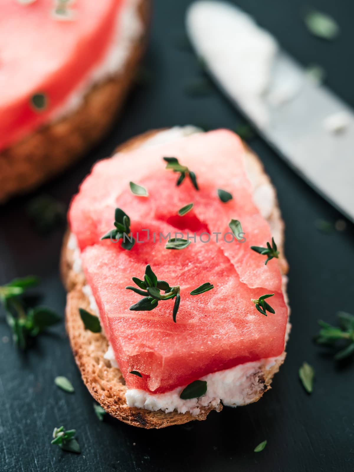 Toasts with soft cheese, watermelon and fresh thyme.Salty cheese,sweet watermelon and spicy thyme on crispy grilled bread slices. Idea and recipe for unusual healthy breakfast, summer snack or lunch