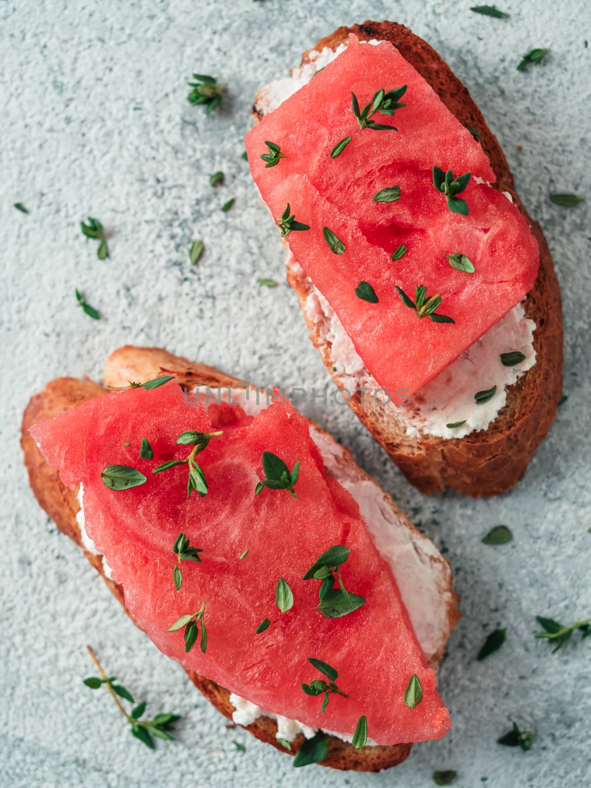 Toasts with soft cheese and watermelon.Salty cheese,sweet watermelon and spicy thyme on crispy grilled bread slices.Idea and recipe for unusual healthy breakfast,summer snack or lunch.Top view flatlay