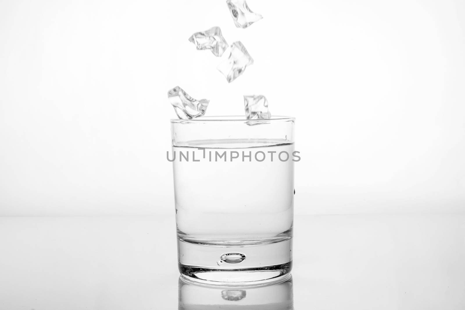 ice cubes falling into a glass of water