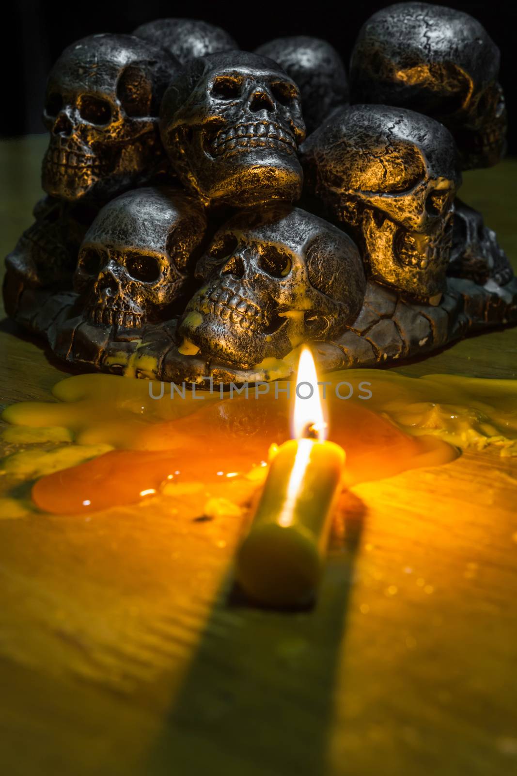 skulls with candle burning on wooden background in the darkness  by ronnarong
