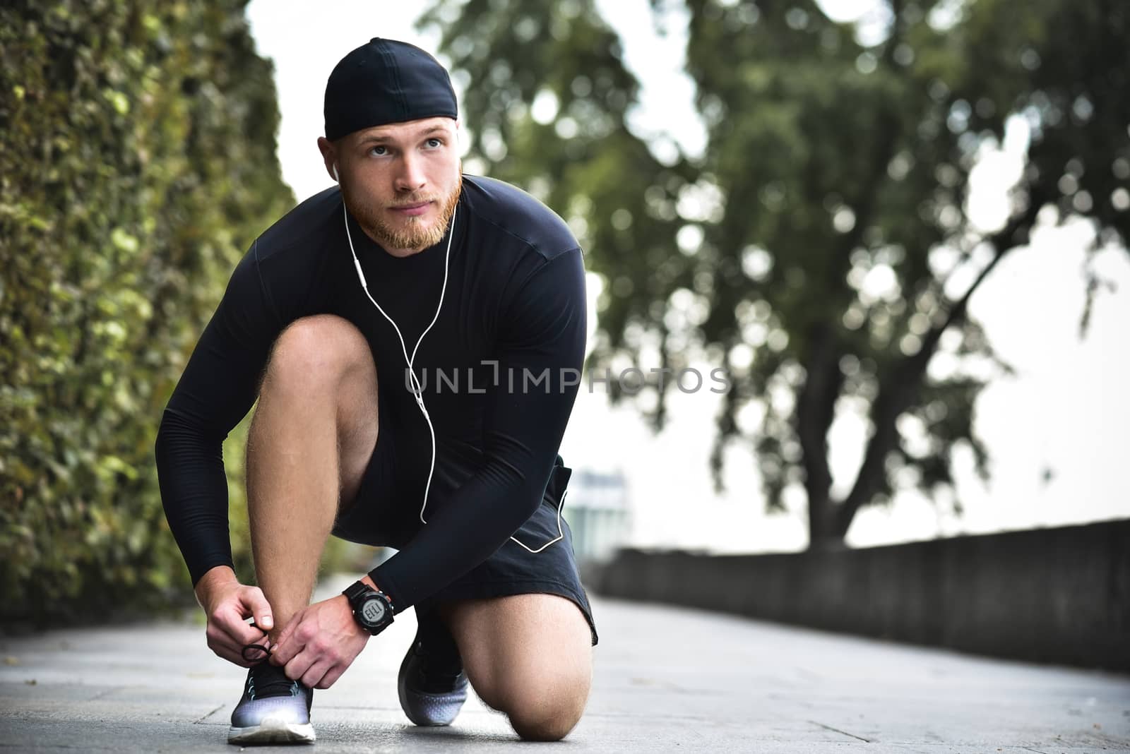 Hands of sportsman with pedometer tying shoelaces on sporty sneaker.