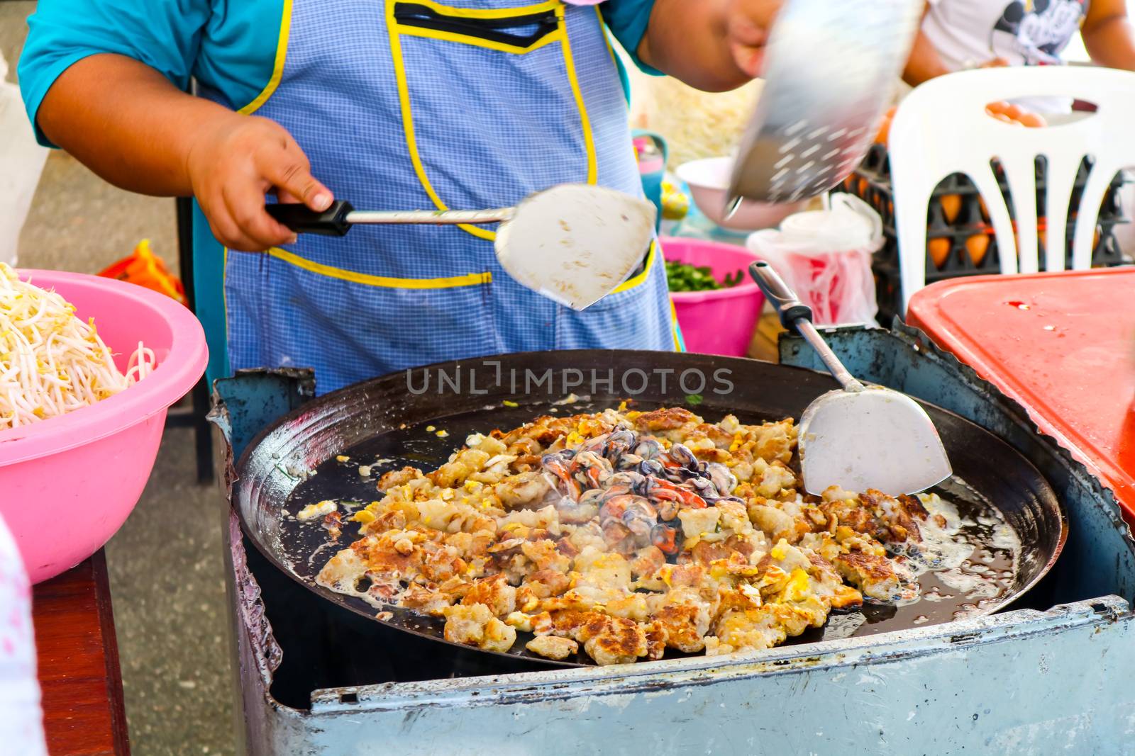The seller is fried and cooking mussel can be seen by street food in Thailand