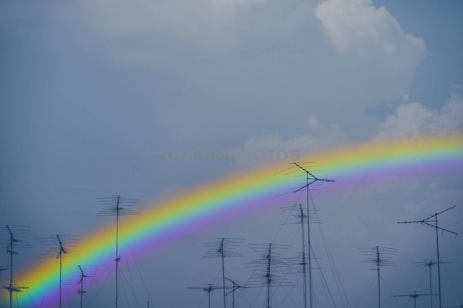 colorful of rainbow back on silhouette antennas on the dark sky