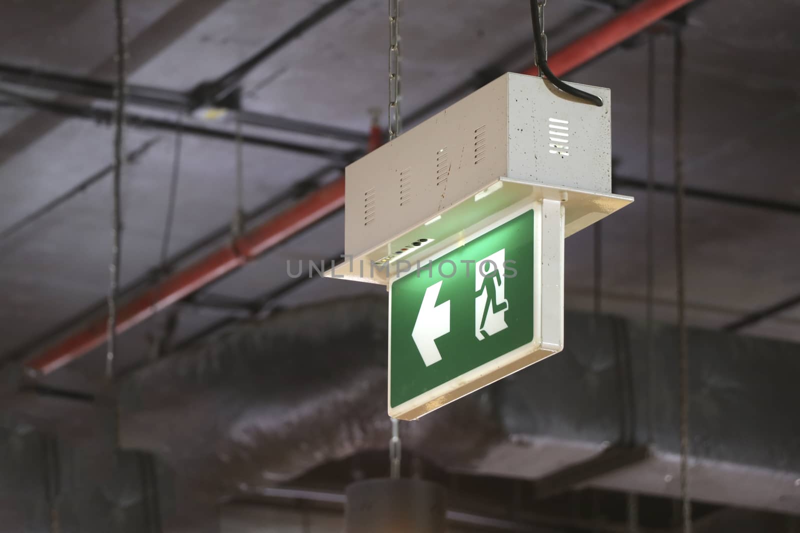 Fire exit sign hanging on top of the building. Fire exit sign indicating safe route.