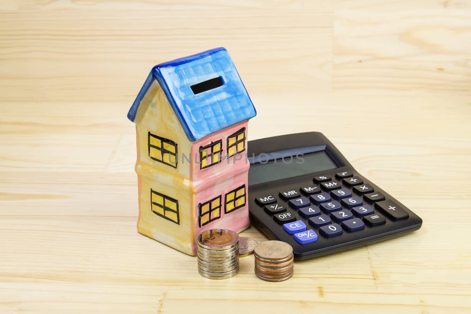 Model house with coin, calculator on wood table, concept 
Collecting money Buying a house, residence, business, finance