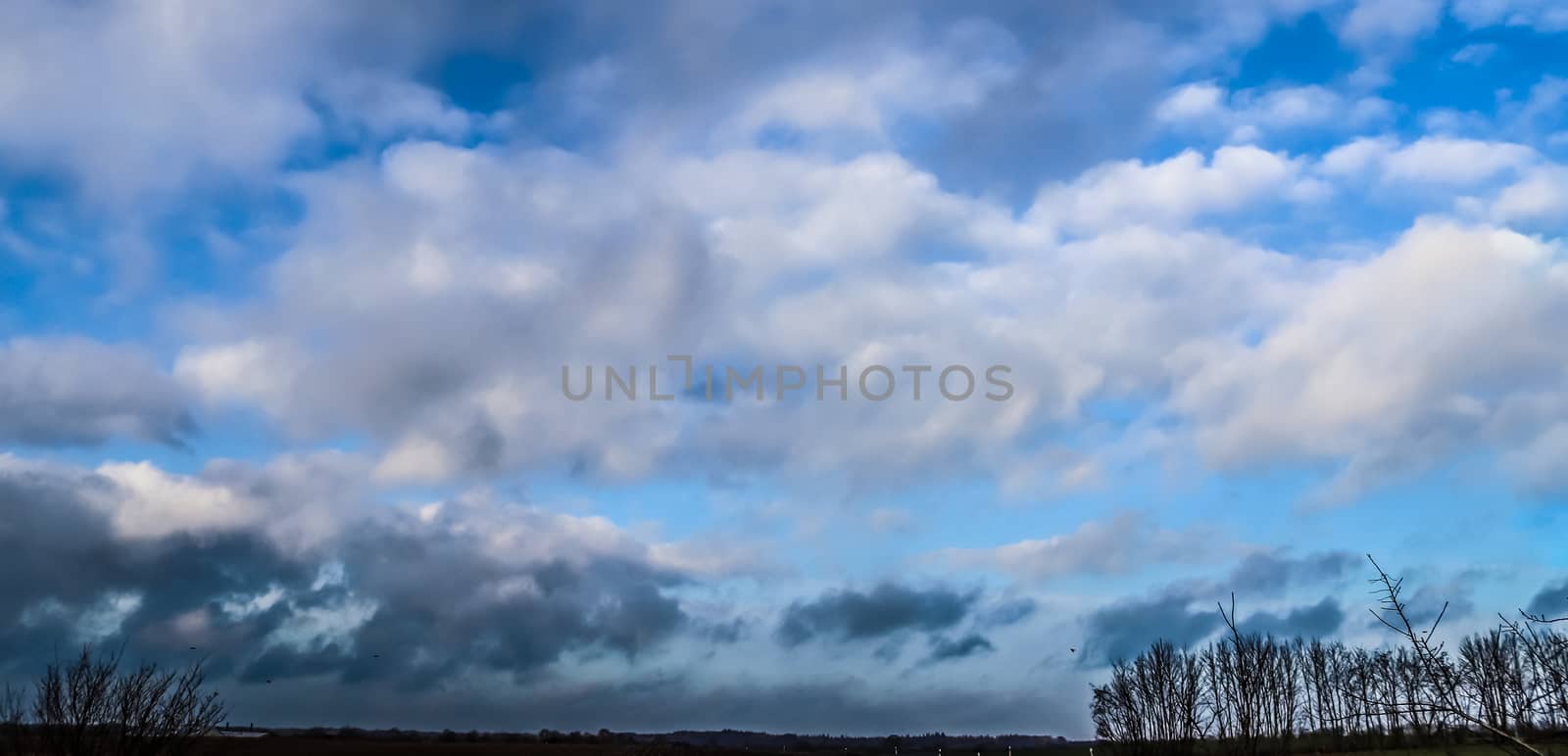 Stunning mixed cloud formation panorama in a deep blue summer sky.