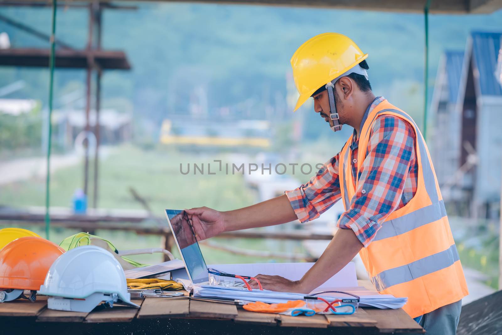 Engineer working with laptop and blueprints. by Visoot