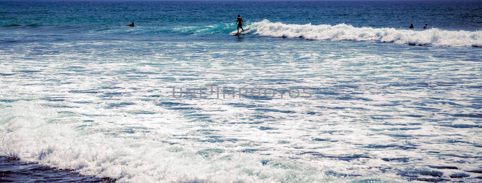 Surfer on a surfboard in the sea water splash blue transparent surf fresh ocean water background island of Bali Indonesia.