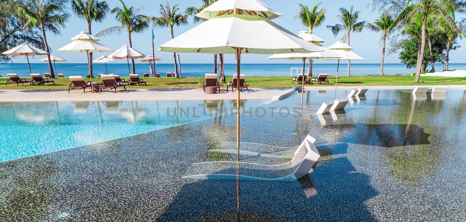 tropical resort hotel with swimming pool. Beach umbrella, beach chair tile floor marble ceramic mosaic. Vacation and travel concept.