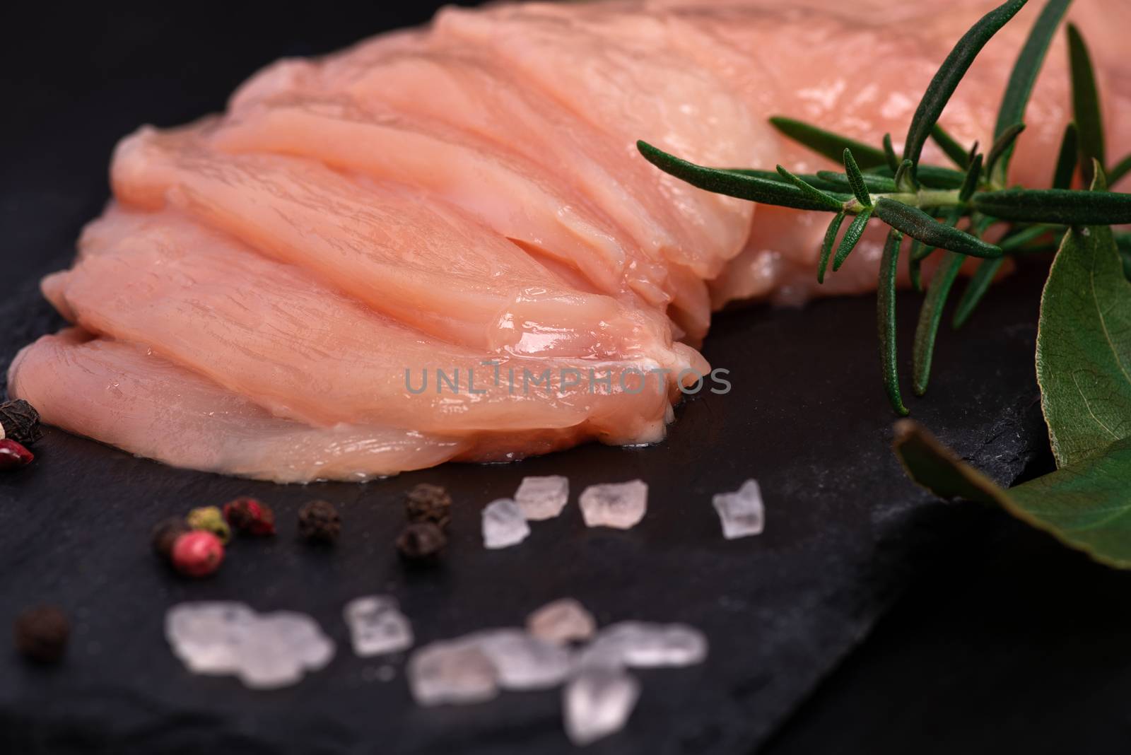 Raw chicken slices on a wooden table with spices. Satilisimo. Close-up view of raw, fresh, choped and sliced chicken meat. Delicious dietary meat.Top view. by nkooume