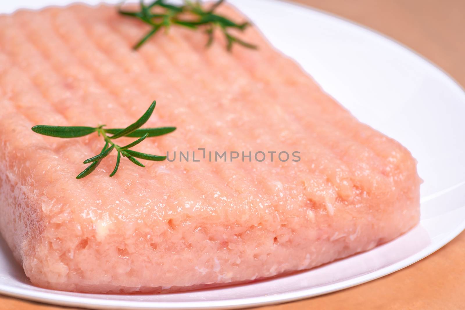 Raw Minced meat with herbs and spices,minced chicken close-up. Raw chicken mince on a white plate and on a white background. Close-up of chicken mince. Delicious diet meat.