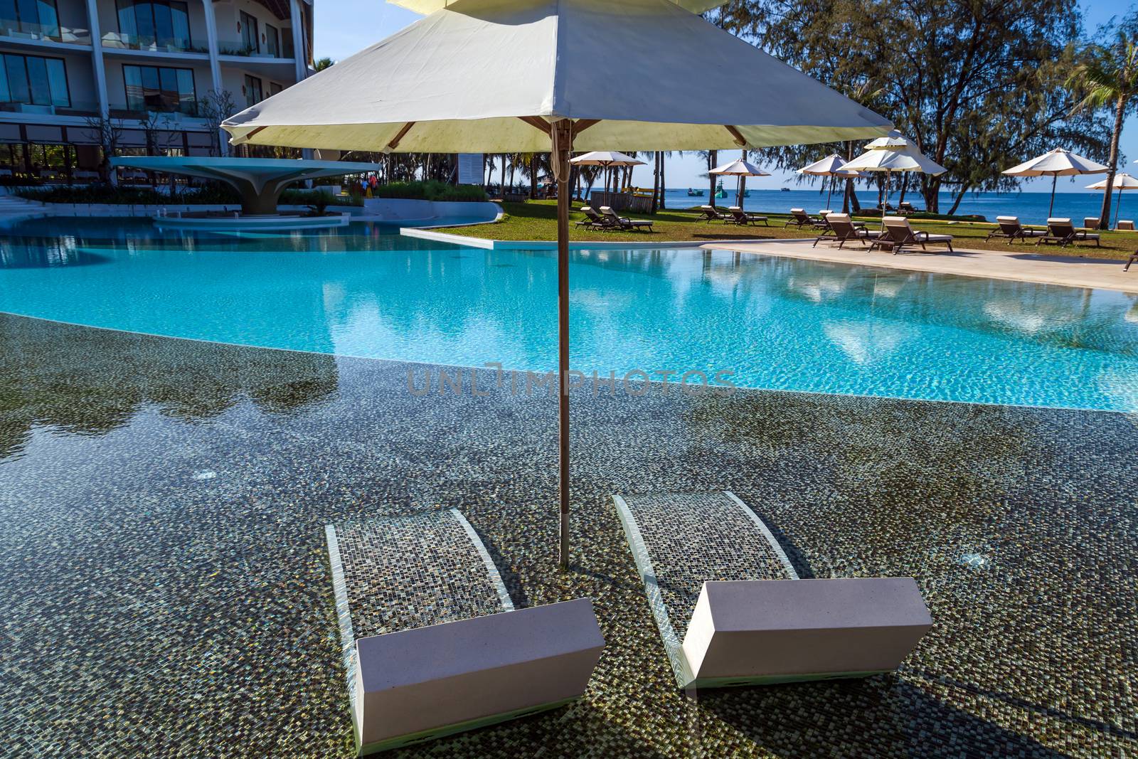 Blue pool. Tropical beach relax deck chairs sun umbrella. Hotel resort - travel vacation.