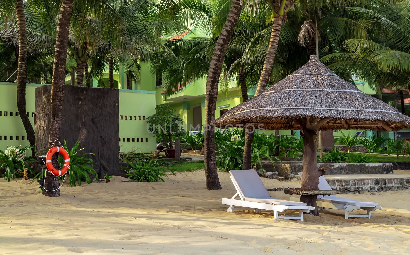 Caribbean Tropical views from Long Beach Phu Quoc Island, Vietnam. Nobody on the beach. Palm tree bamboo umbrellas and sun chairs in background.