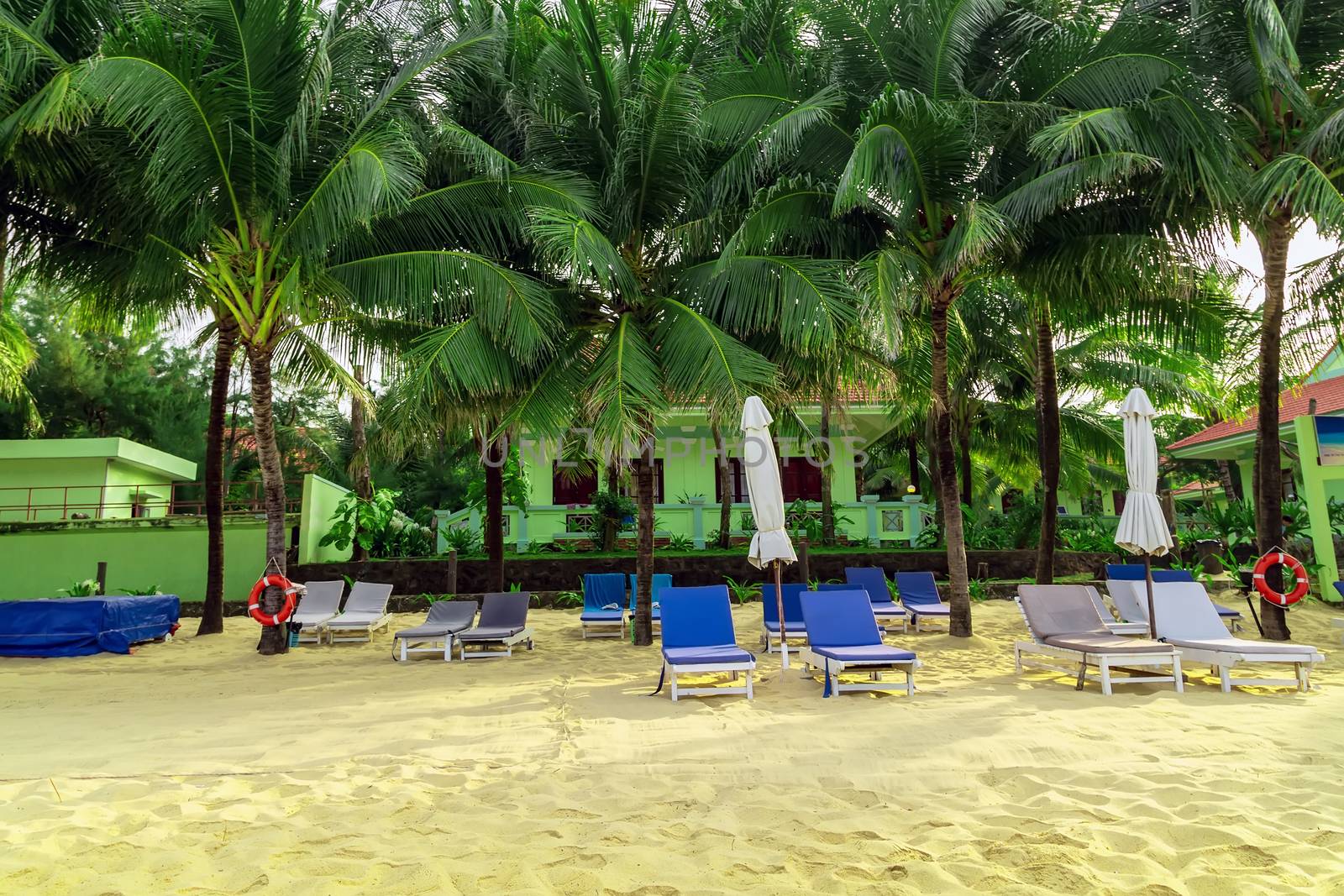 Tropical views from Long Beach Phu Quoc Island, Vietnam. Nobody on the beach. Palm tree bamboo umbrellas and sun chairs in background.
