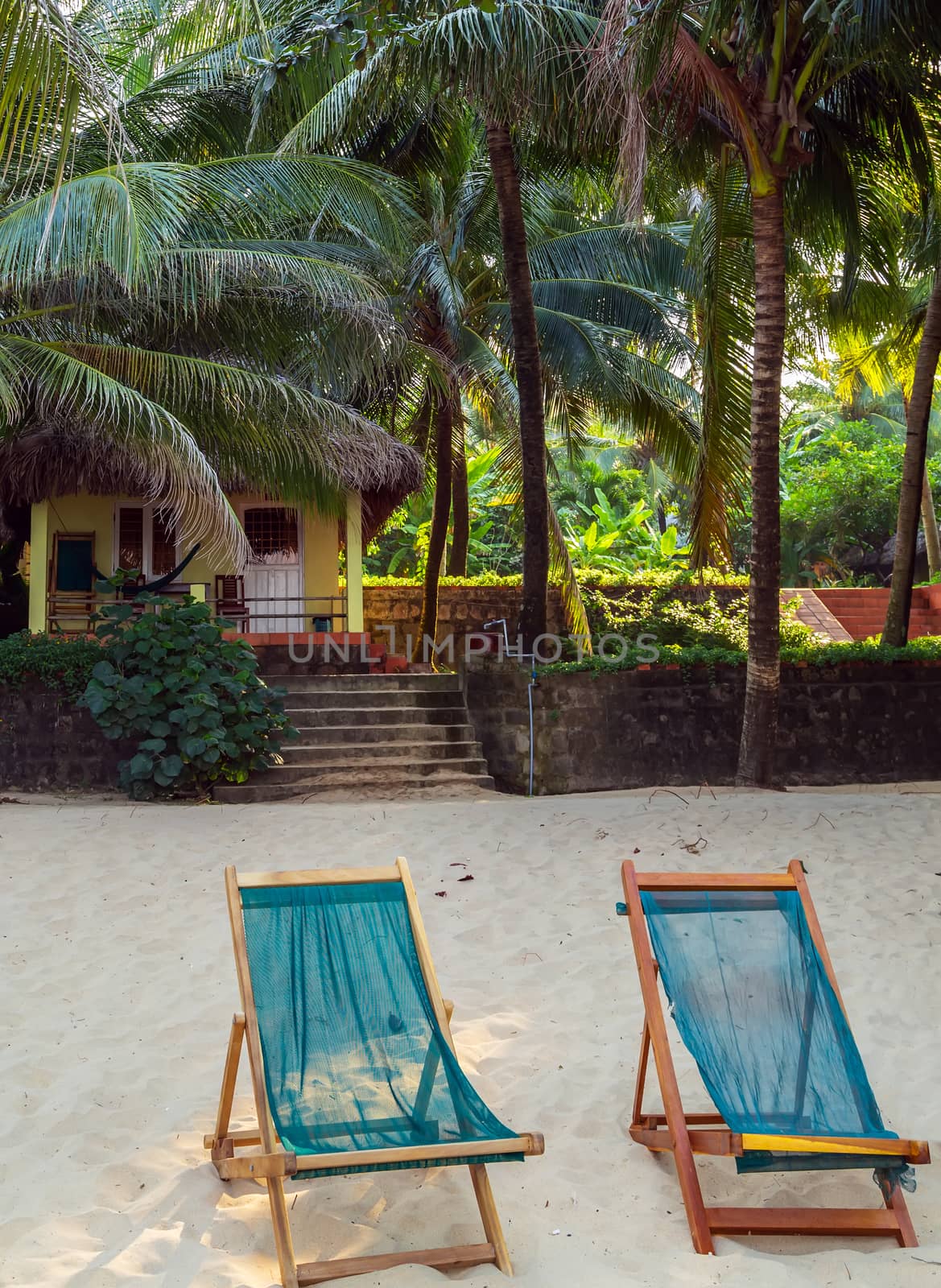 Rest sand beach with beach chairs. Maldives island, white sandy beach and sea. Luxury beach resort or hotel, beach villas and two sun chairs with sun umbrella under palm trees on white sand.