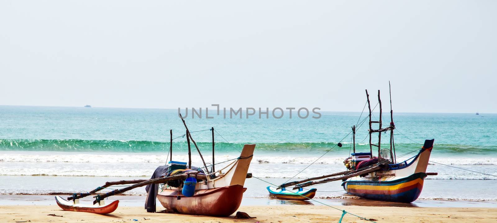 OLD traditional fishing catamarans, Colorful fishing boats on a long sandy beach on the ocean coast of Sri Lanka. Popular landmark fishing Ceylon village.