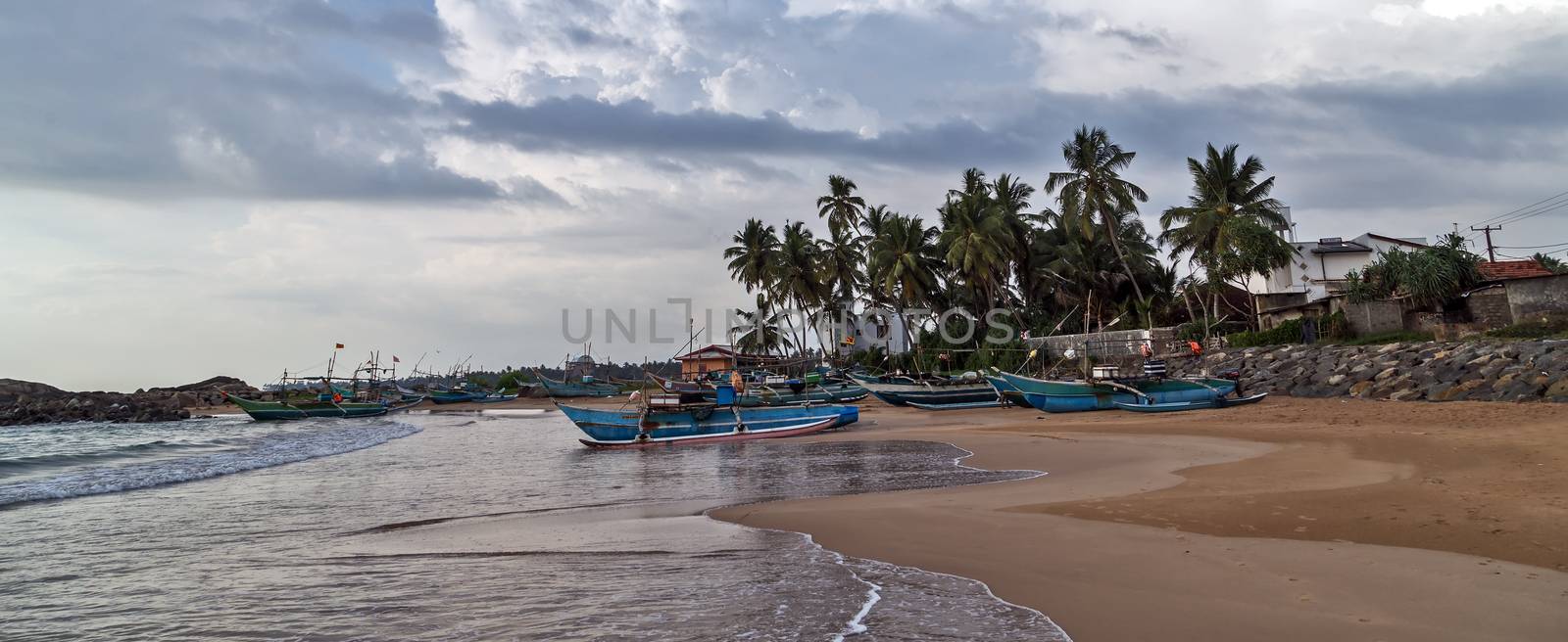 Sri Lankan traditional fishing catamarans, Colorful fishing boats on a long sandy beach on the ocean coast of Sri Lanka. Popular landmark fishing