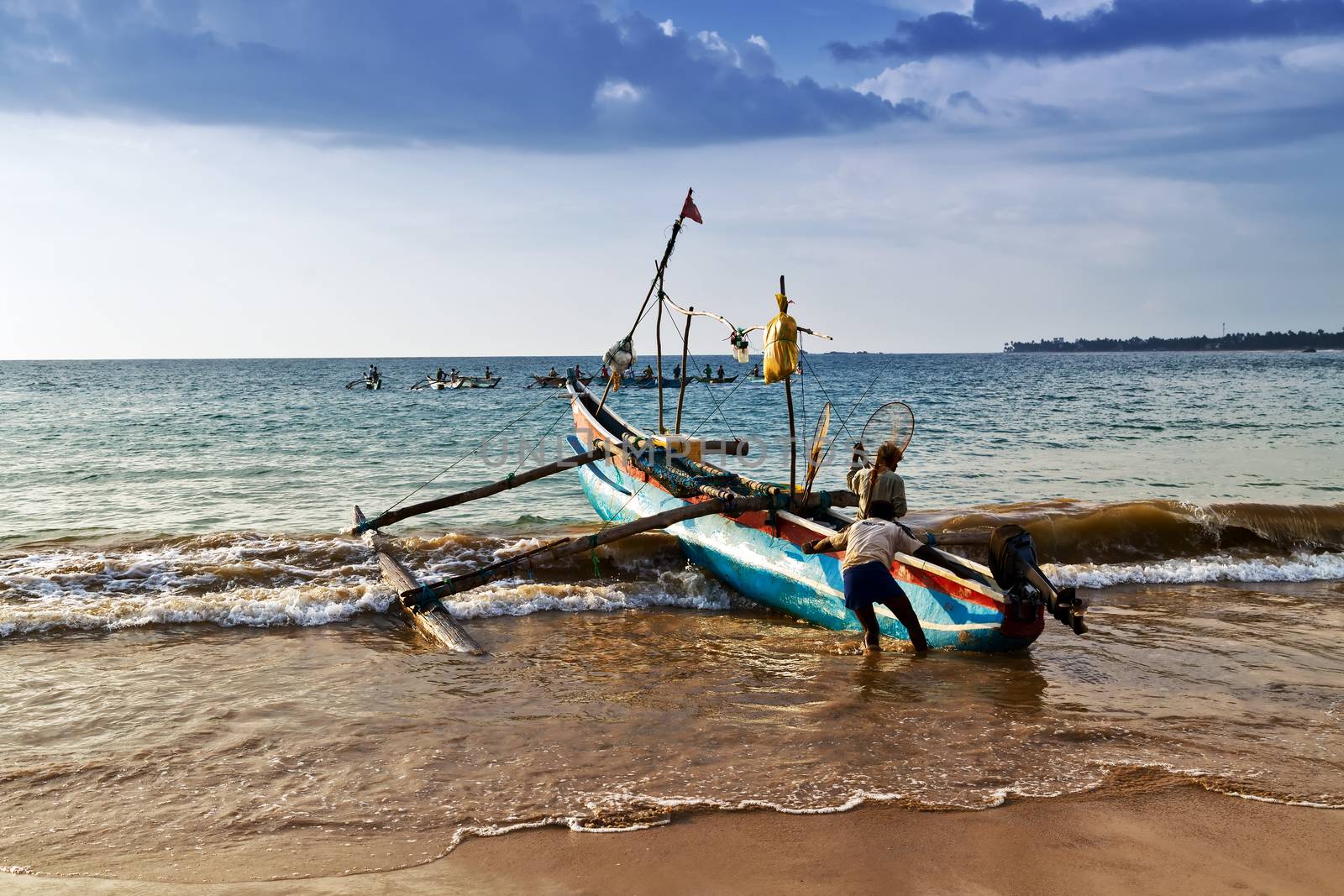 Sri Lankan traditional fishing catamaran Colorful fishing boats on a long sandy beach on the ocean coast of Sri Lanka. fishing Ceylon village.