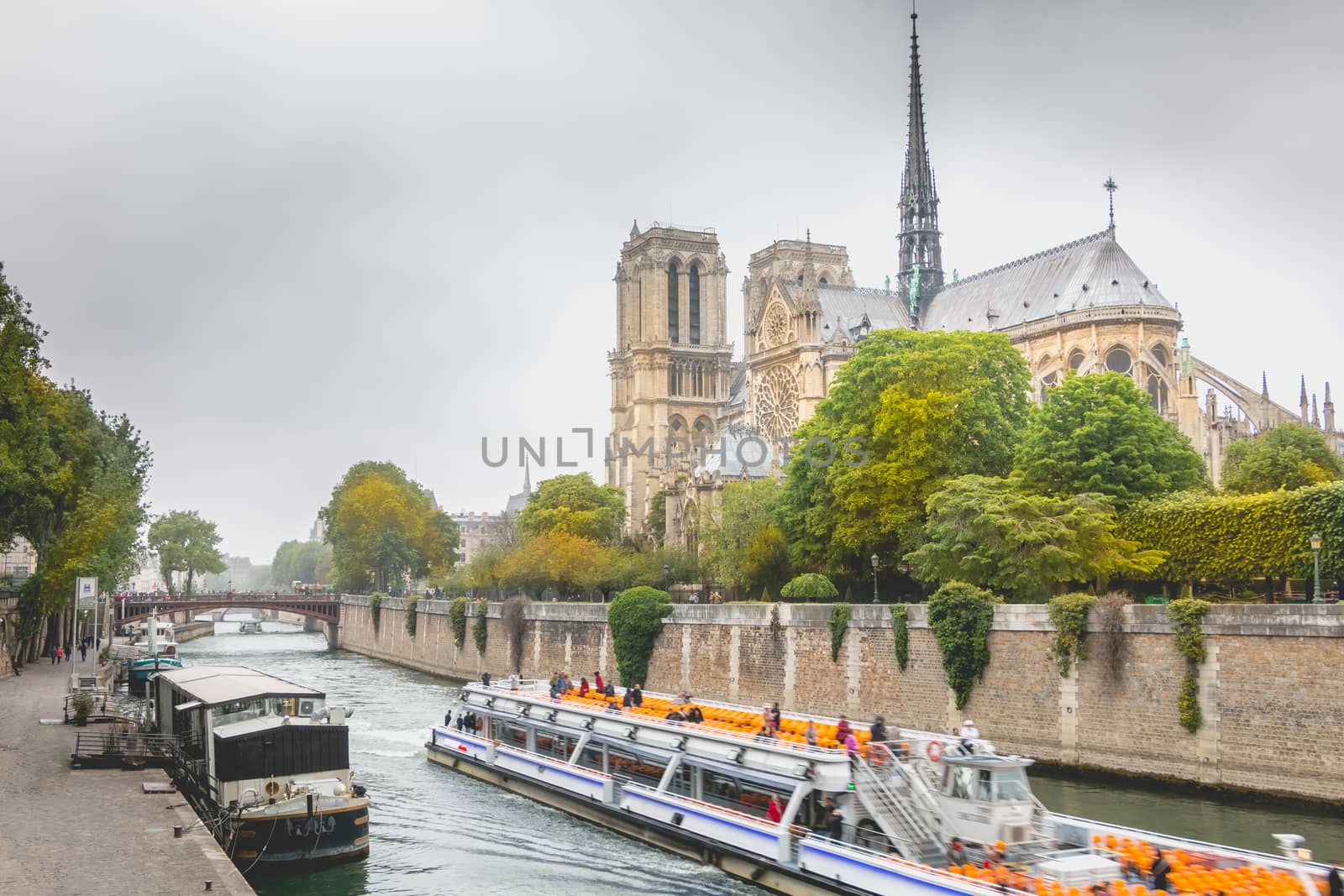 Paris, France - May 8, 2017 - Side view of Notre Dame Cathedral on the Seine with barges on a spring day