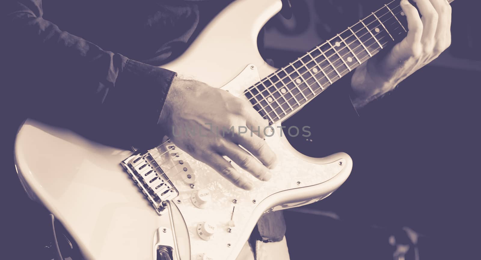 Close up of hands of a man playing a electric guitar. black and white image