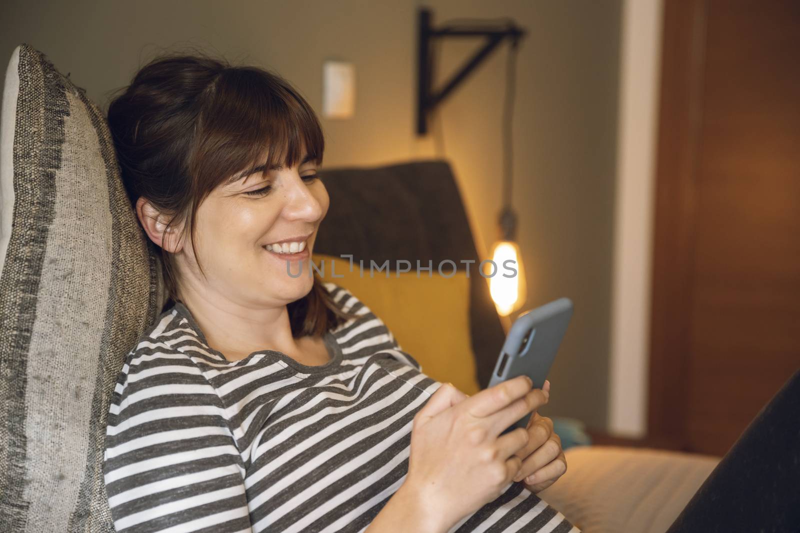 Woman on her bedroom, having a great chat at phone