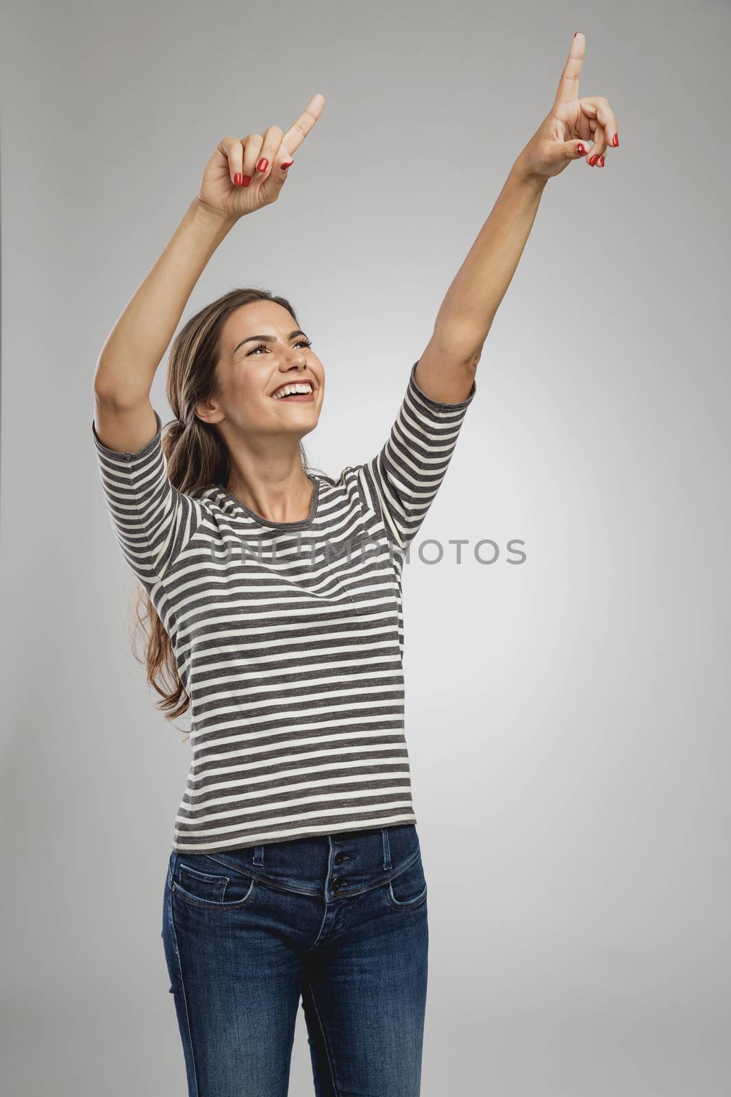 Portrait of a beautiful happy woman looking up and pointing to the sky