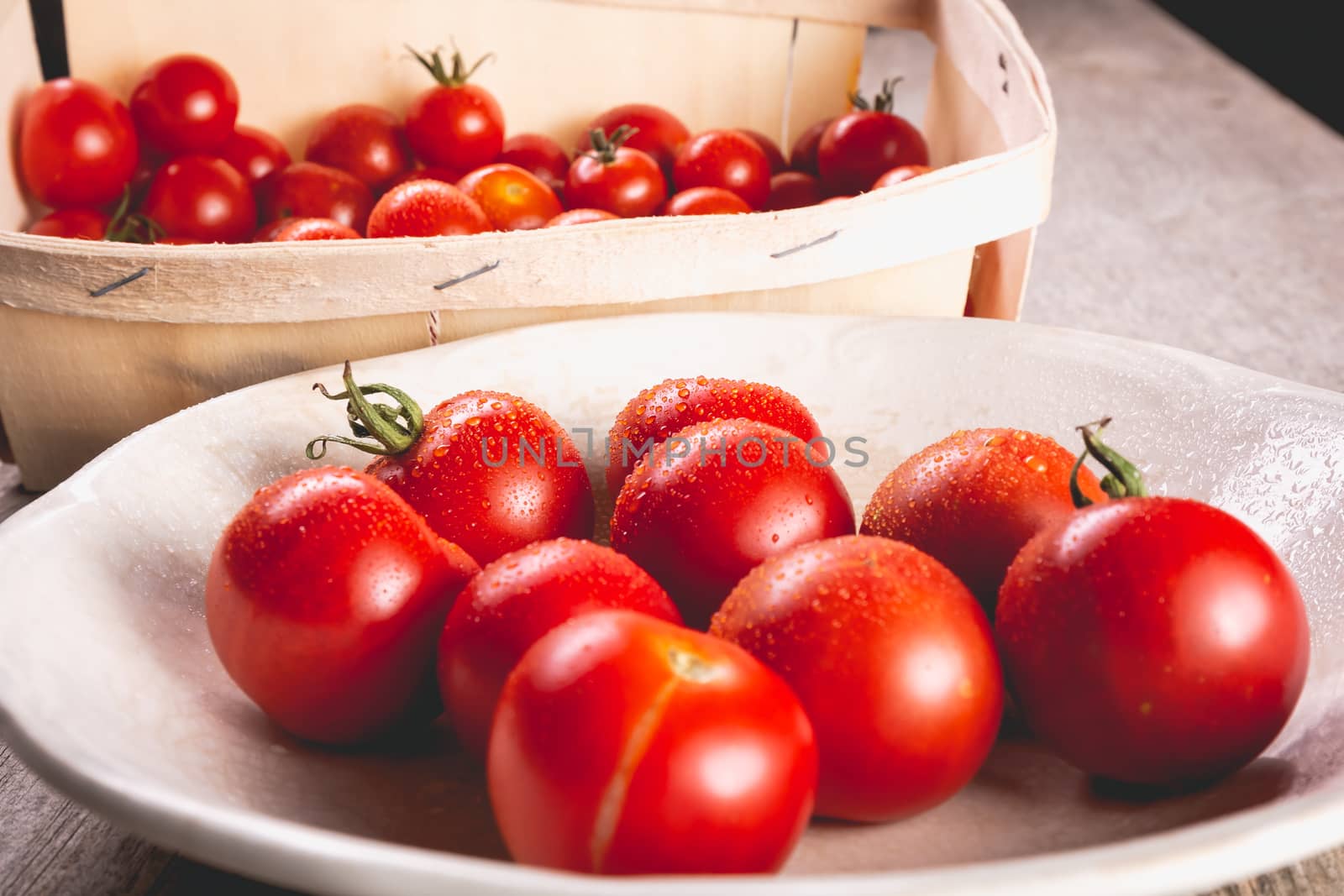 ripe tomatoes in a small wooden crate and old plate in studio