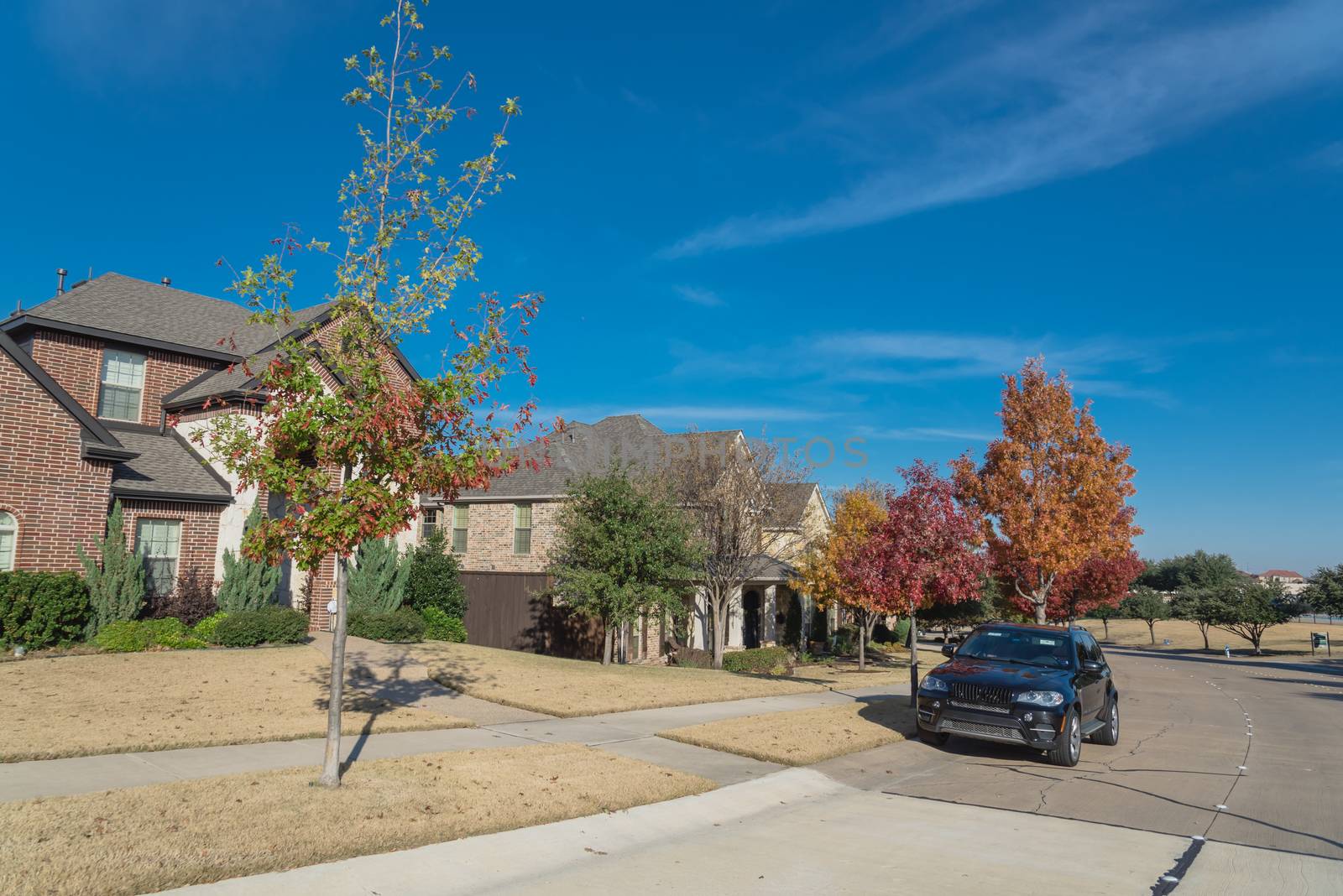 Typical front porch entrance of new suburban houses with parked car on colorful fall street outside Dallas, Texas, USA by trongnguyen