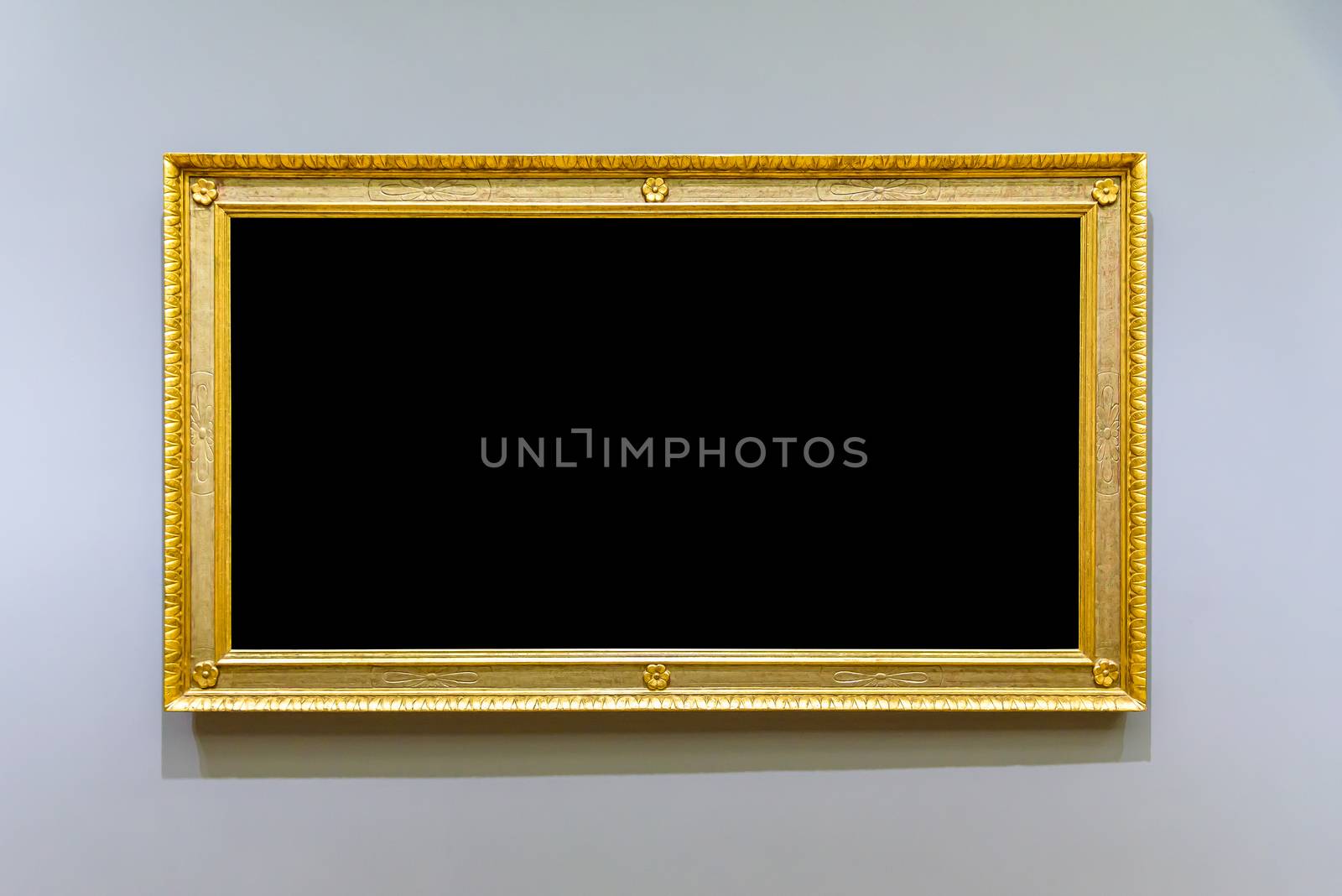 Empty golden picture frame on the gray wall