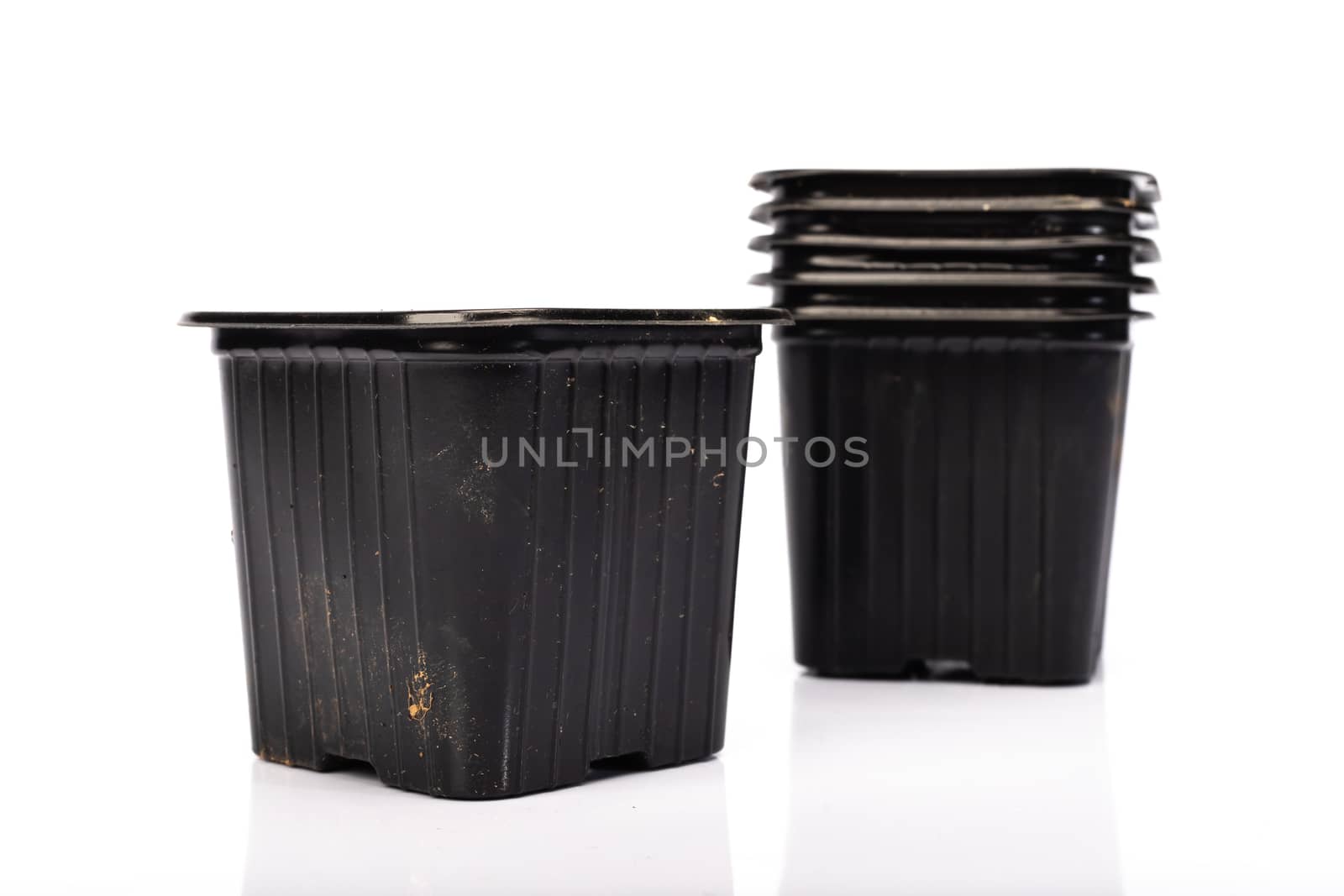 used black plastic gardening bucket waiting for spring on white background in studio