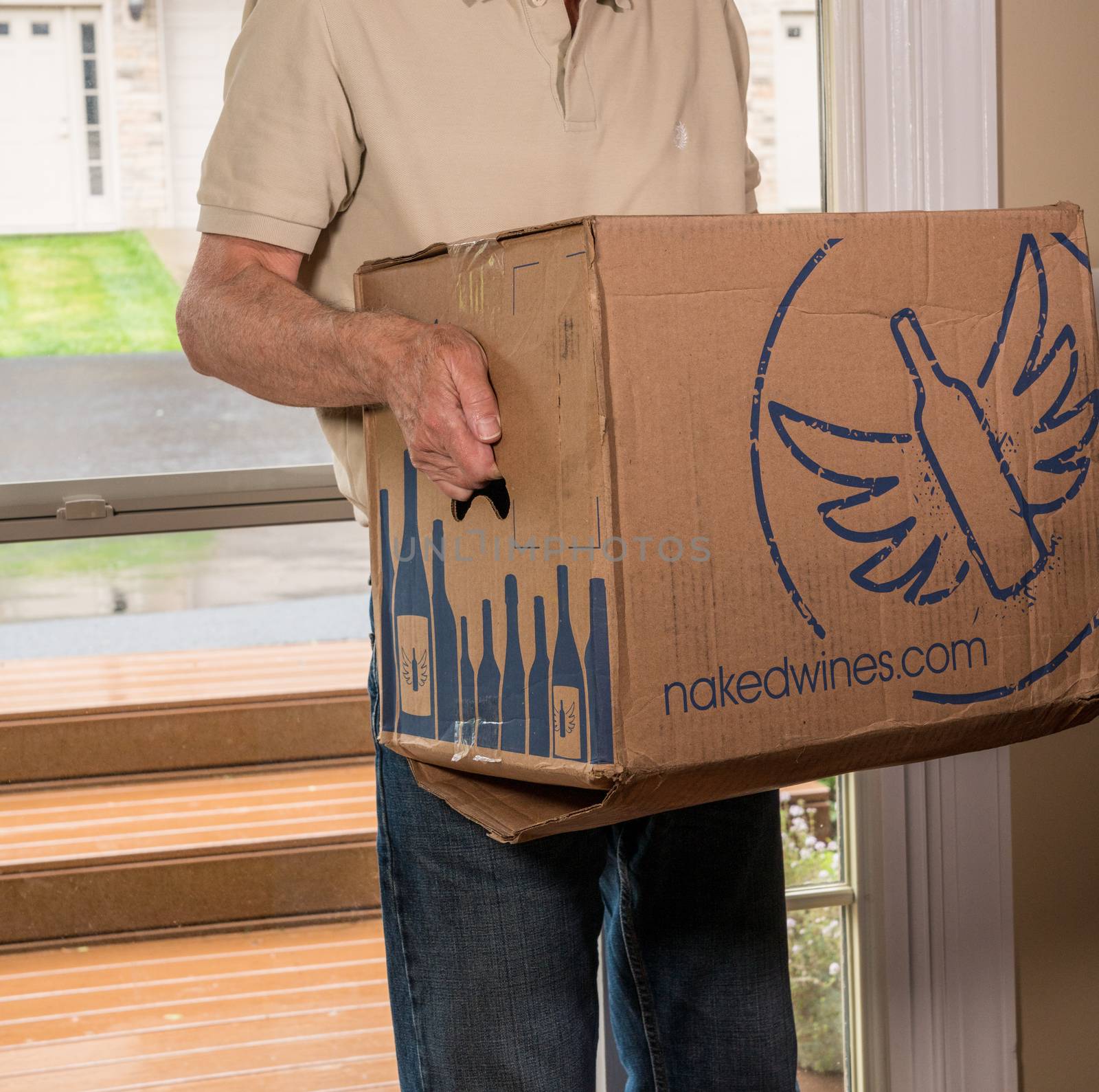 Morgantown, WV - 19 May 2020: Man carrying delivery case of a dozen wine bottles from Naked Wines into home