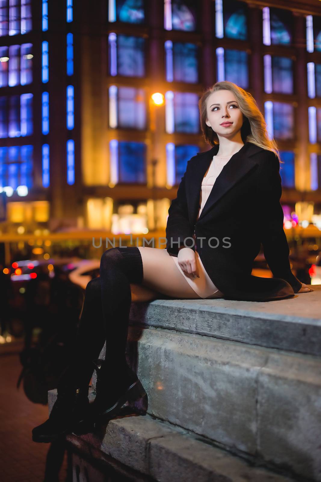 portrait of Beautiful young woman in black on a background of a night city by Nickstock