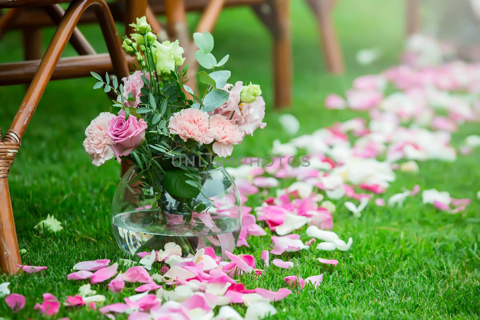 Outdoor wedding ceremony decoration setup. Path with petals, chairs decorated with colorful ribbons