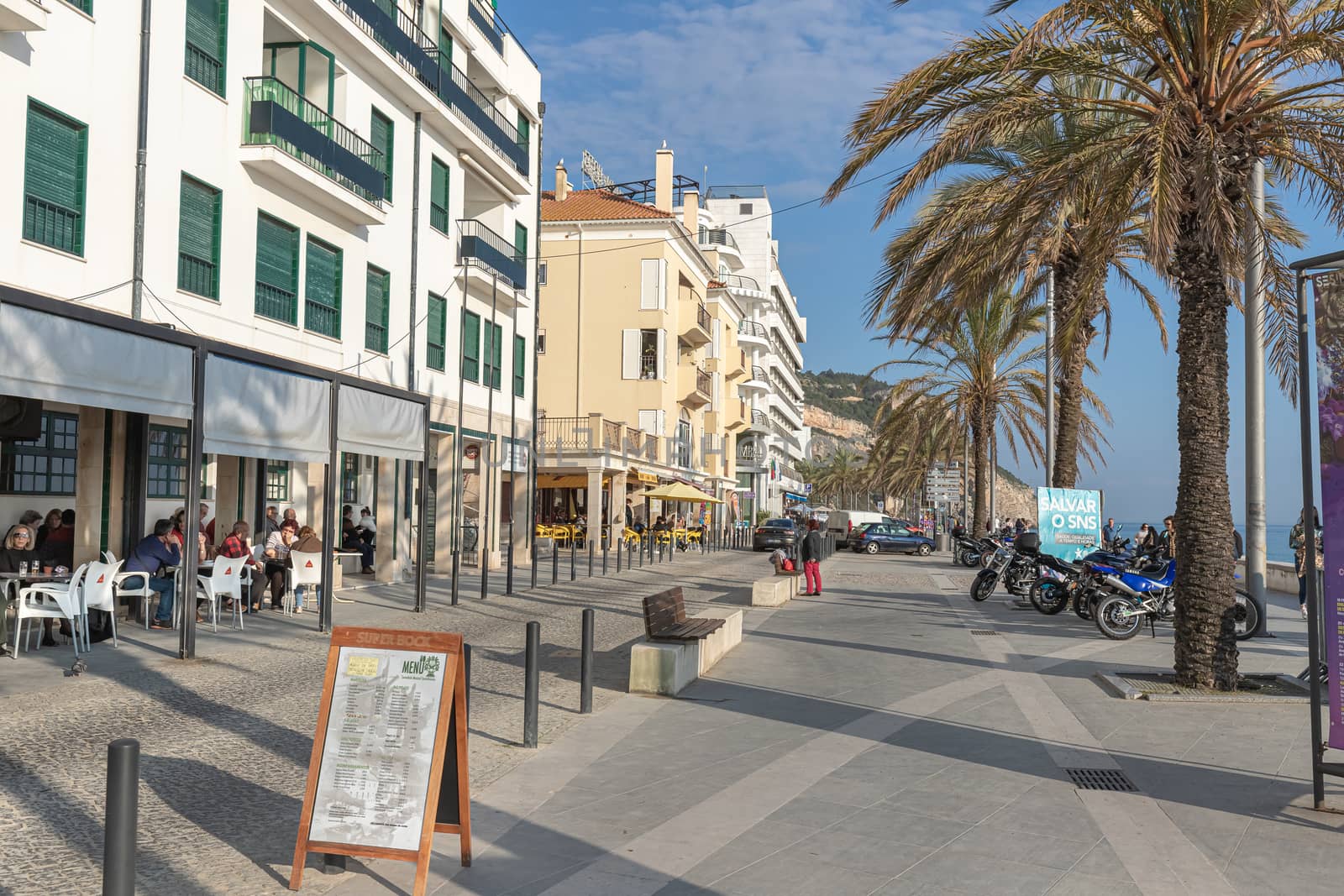 Sesimbra, Portugal - February 20, 2020: View of the city center of Sesimbra by the sea where people are walking on a winter day