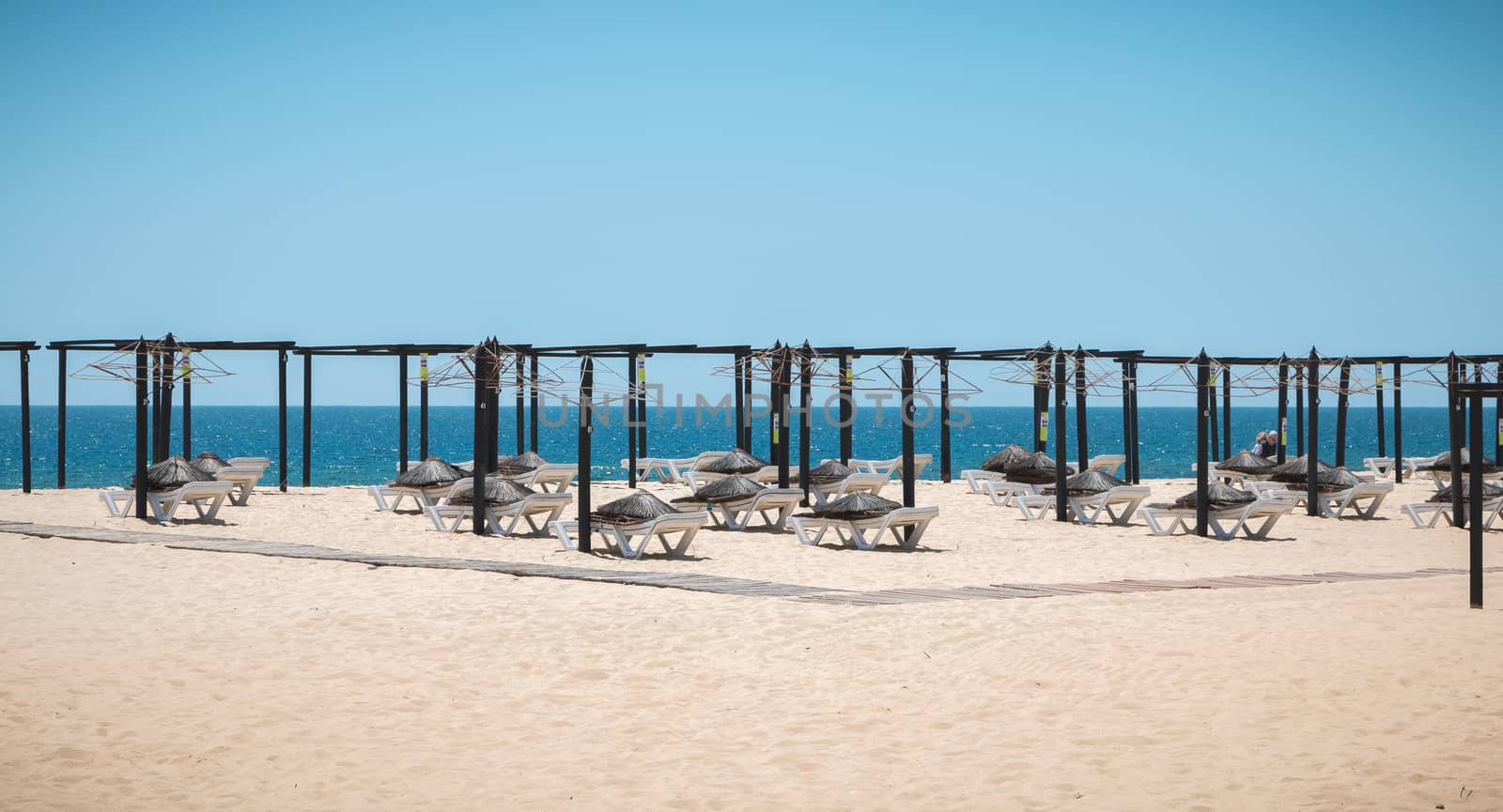 deckchairs and umbrellas stored on the fine sandy beach of tavir by AtlanticEUROSTOXX