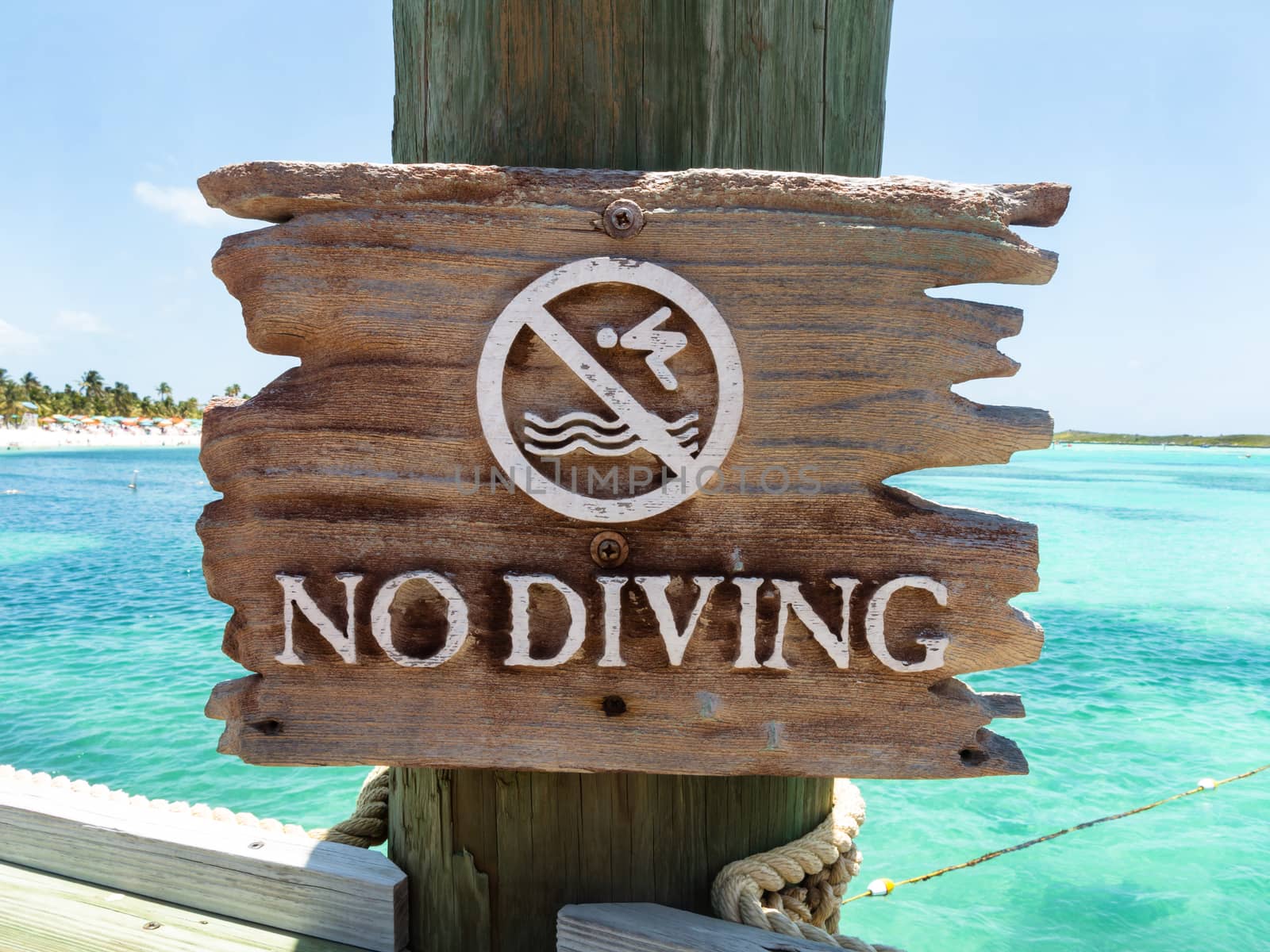 A sign that reads no diving with the ocean behind