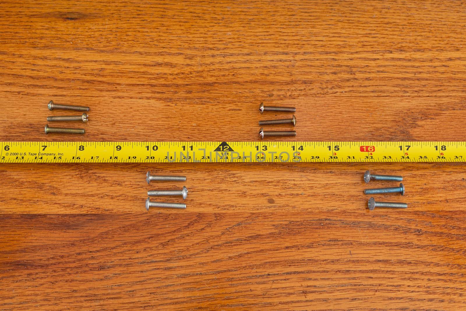 4 sets of 3 screws and a tape measure on wood