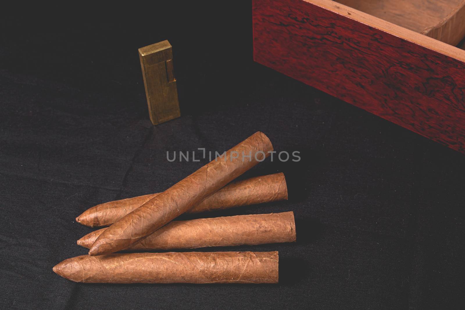 Cigar box on black background and gold lighter