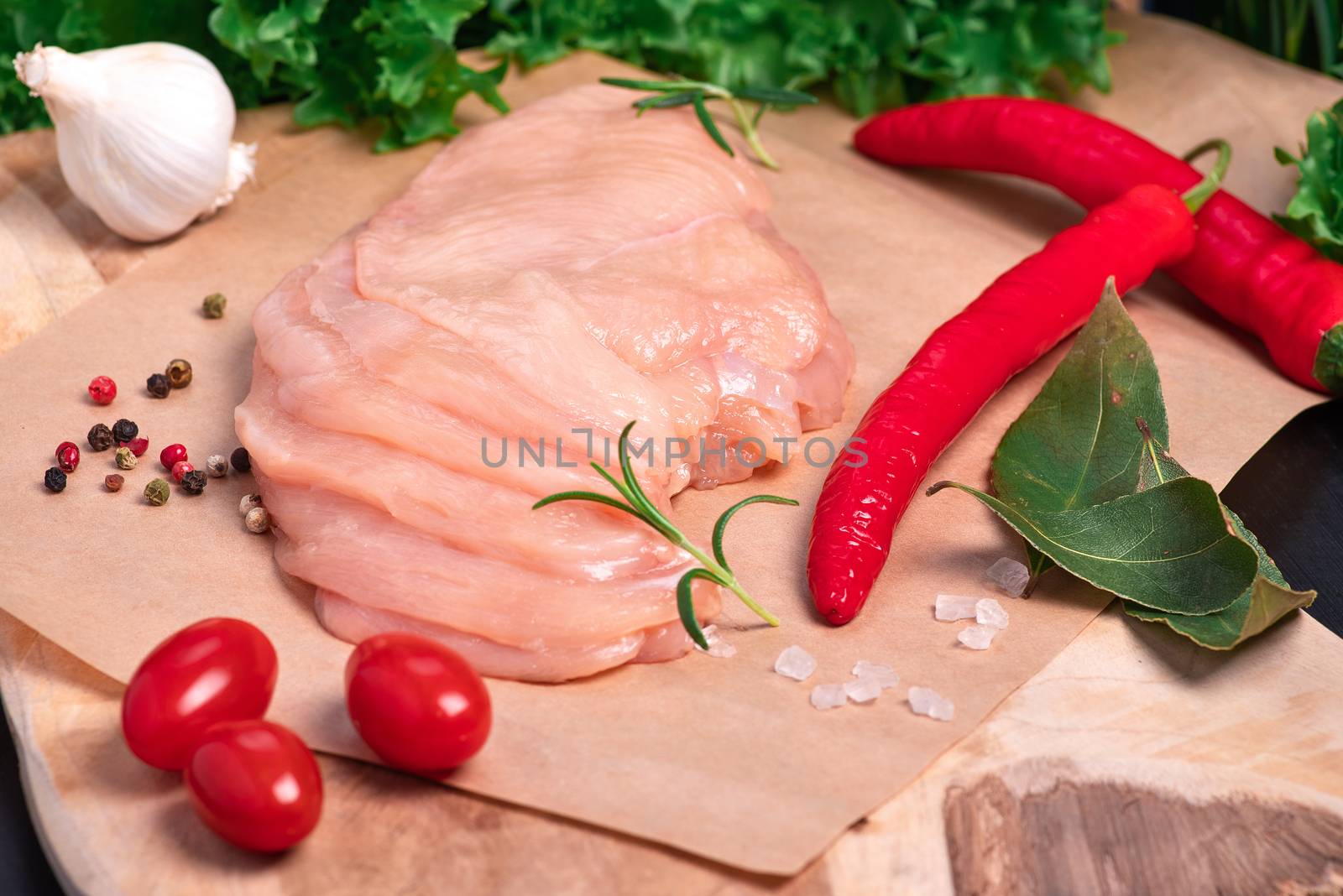 Raw chicken slices on a wooden table with raw vegetables and spices. Satilisimo. Close-up view of raw, fresh, choped and sliced chicken meat. Cooking,raw sliced chicken breast.Top view. by nkooume
