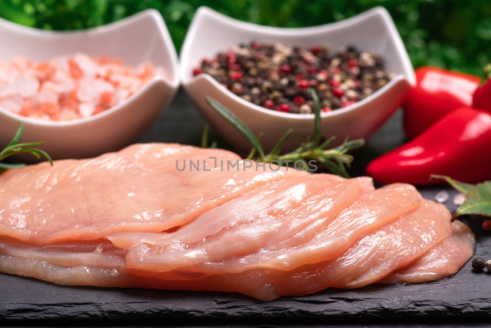 Raw chicken slices on a wooden table with raw vegetables and spices. Satilisimo. Delicious dietary meat. Close-up view of raw, fresh, choped and sliced chicken meat. Cooking,raw sliced chicken breast. by nkooume