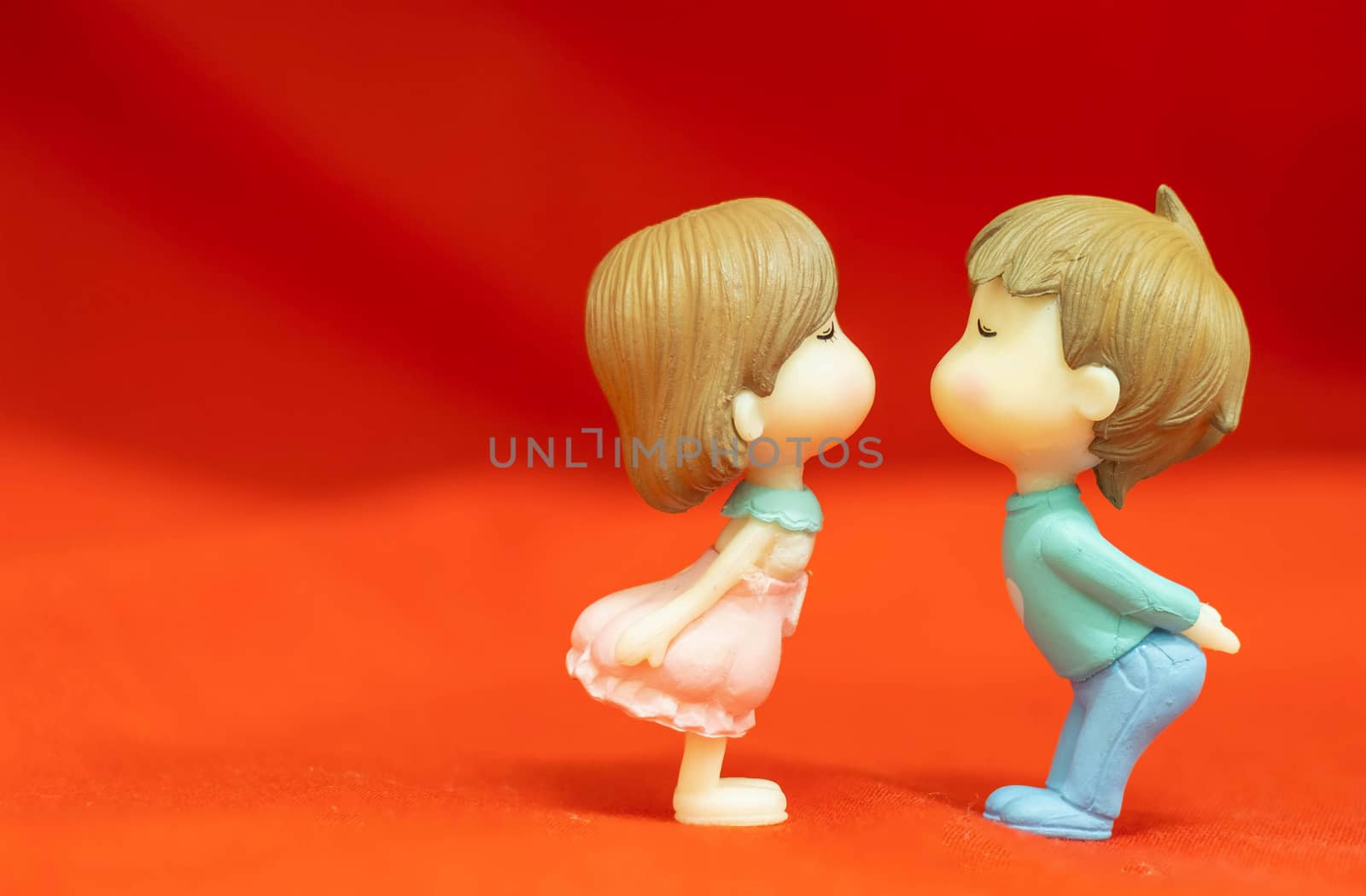 The Miniature Couple dolls Boy and Girl Romantic Kiss on Red Background for valentine's Day Concept