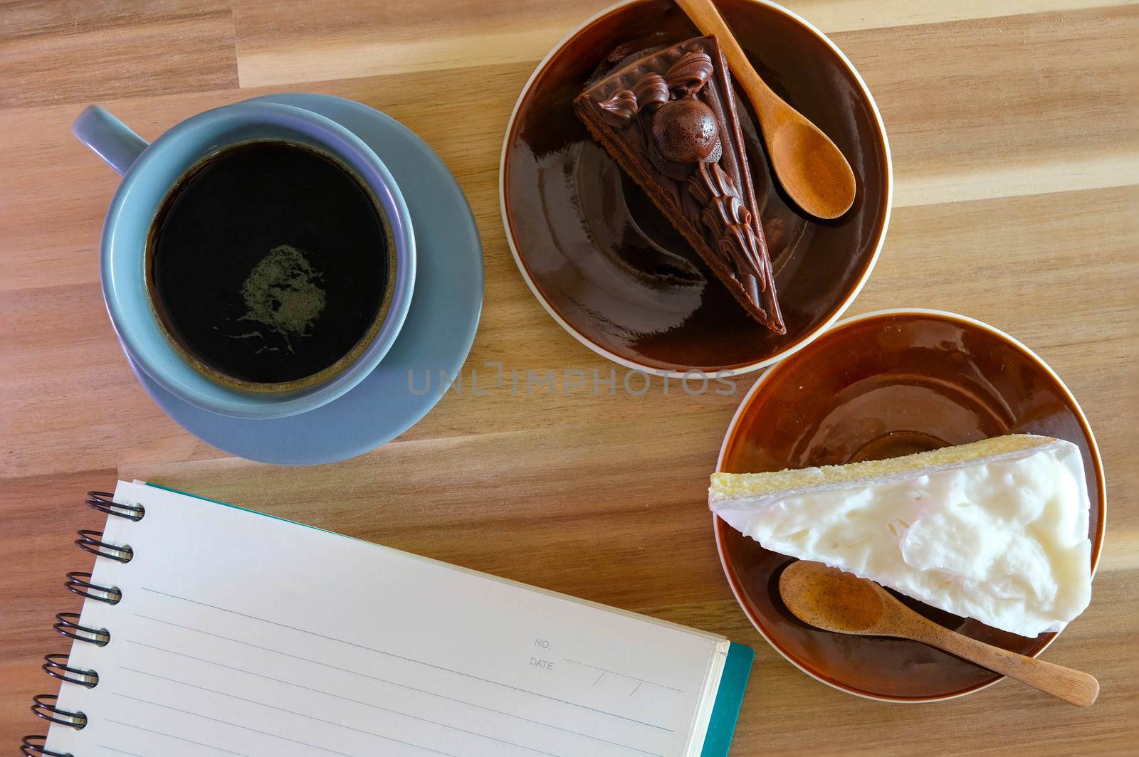 notebook, coffee, chocolate cake and Coconut cake on wooden background