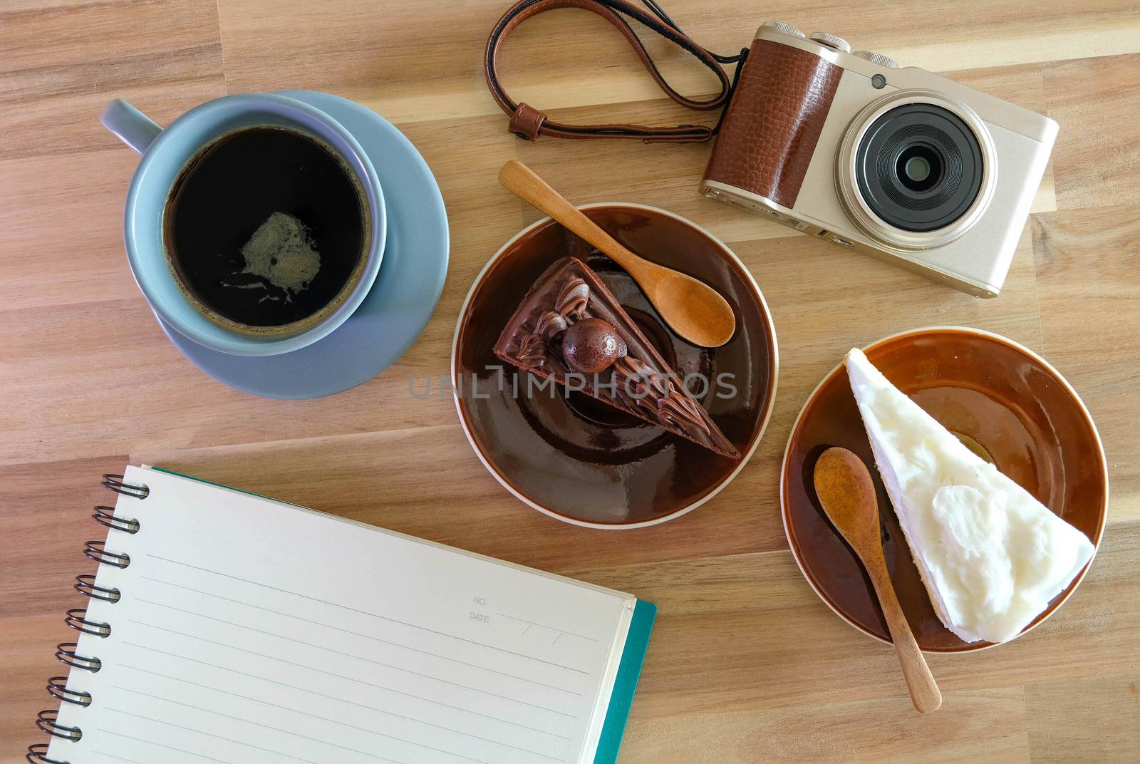 notebook, camera,  coffee, chocolate cake and Coconut cake on wooden background