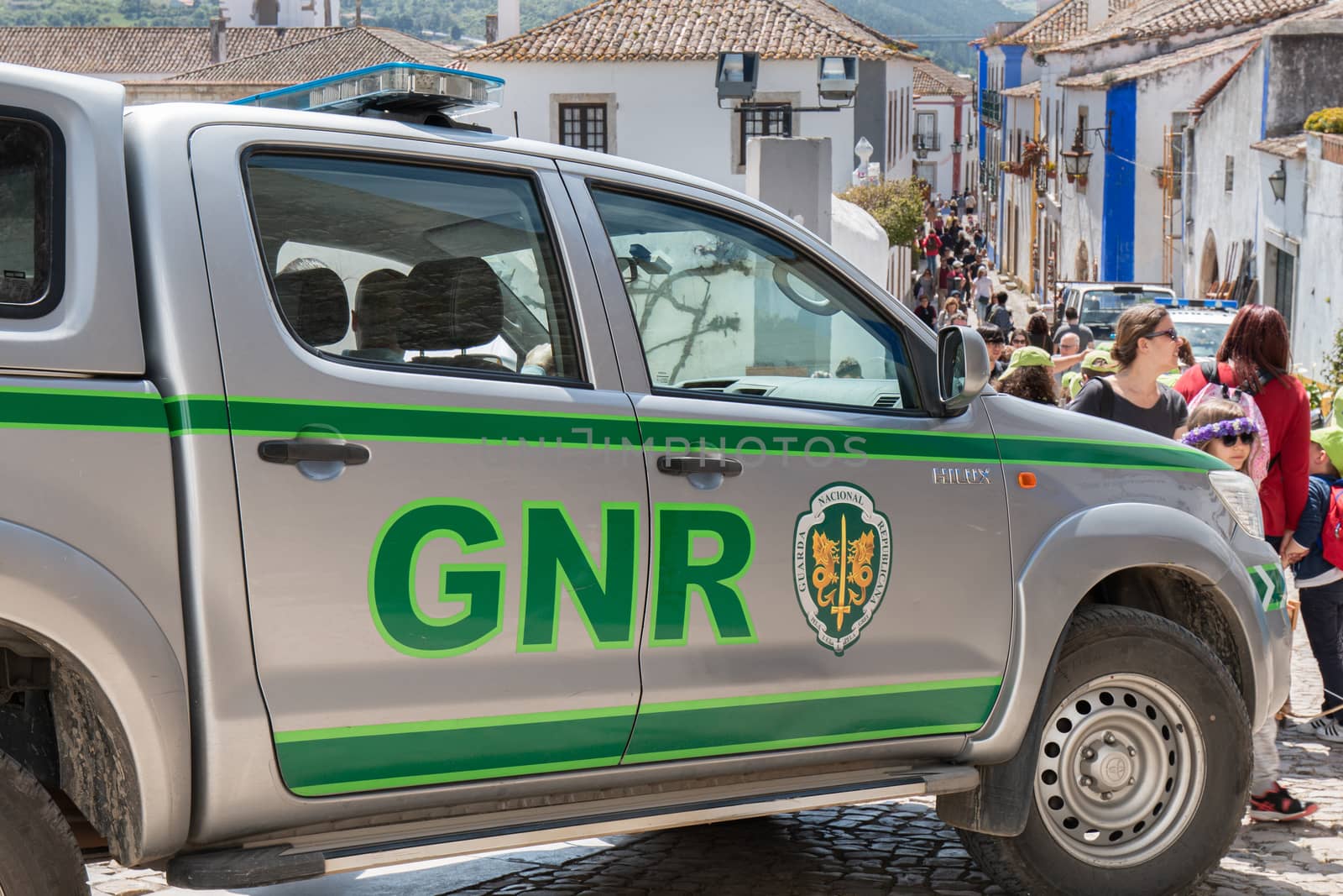 Obidos, Portugal - April 12, 2019: car of the Republican National Guard (GNR) parked in the middle of a pedestrian street where tourists pass on a spring day