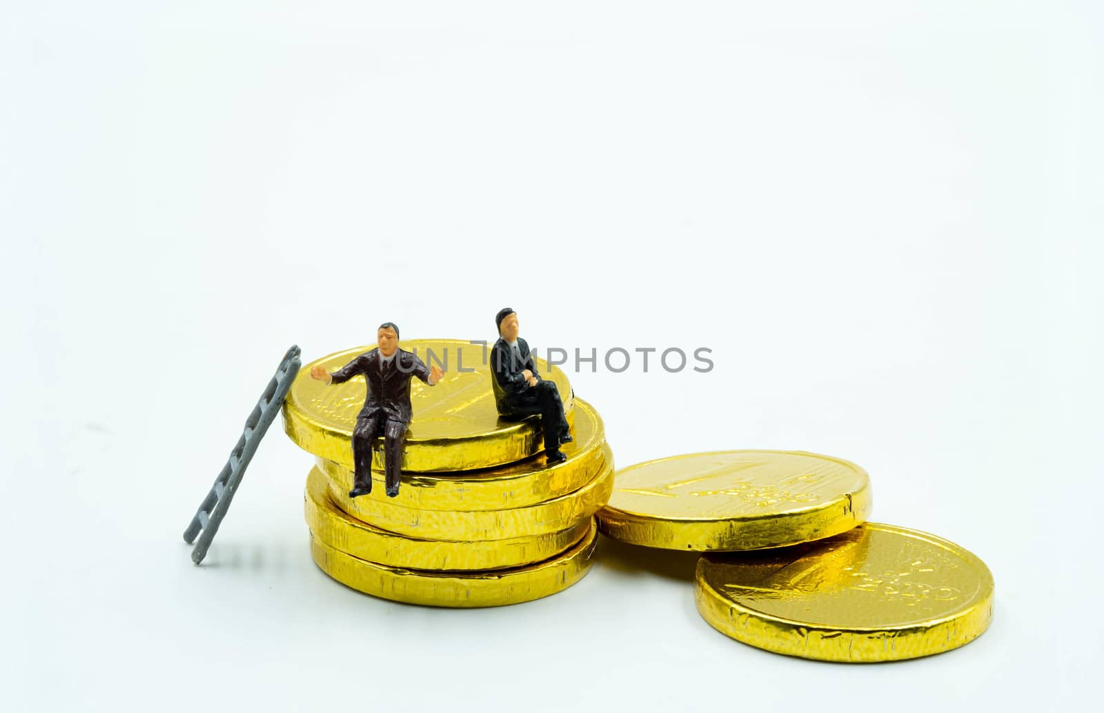 miniature figure a group of business men sitting on top of pile stack of golden coins. business success concept