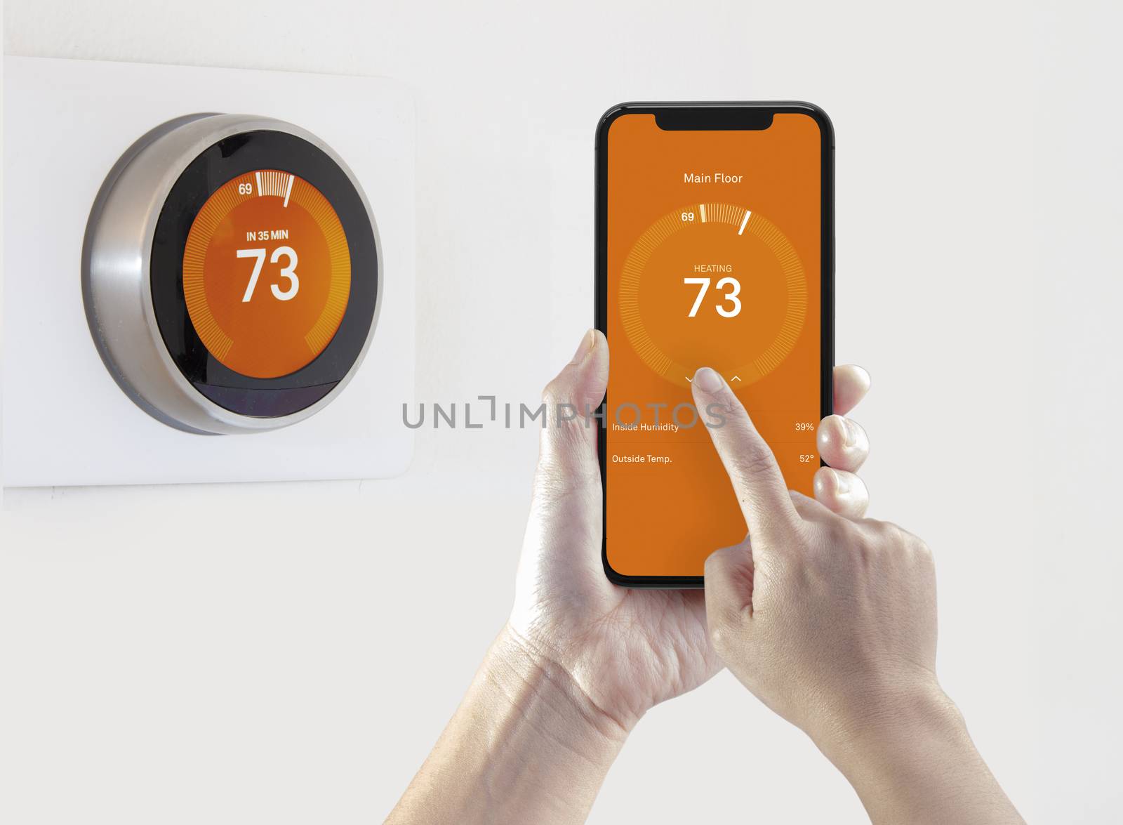 A person using a smart phone application warming up the room temperature with a wireless smart thermostat on a white background. by oasisamuel