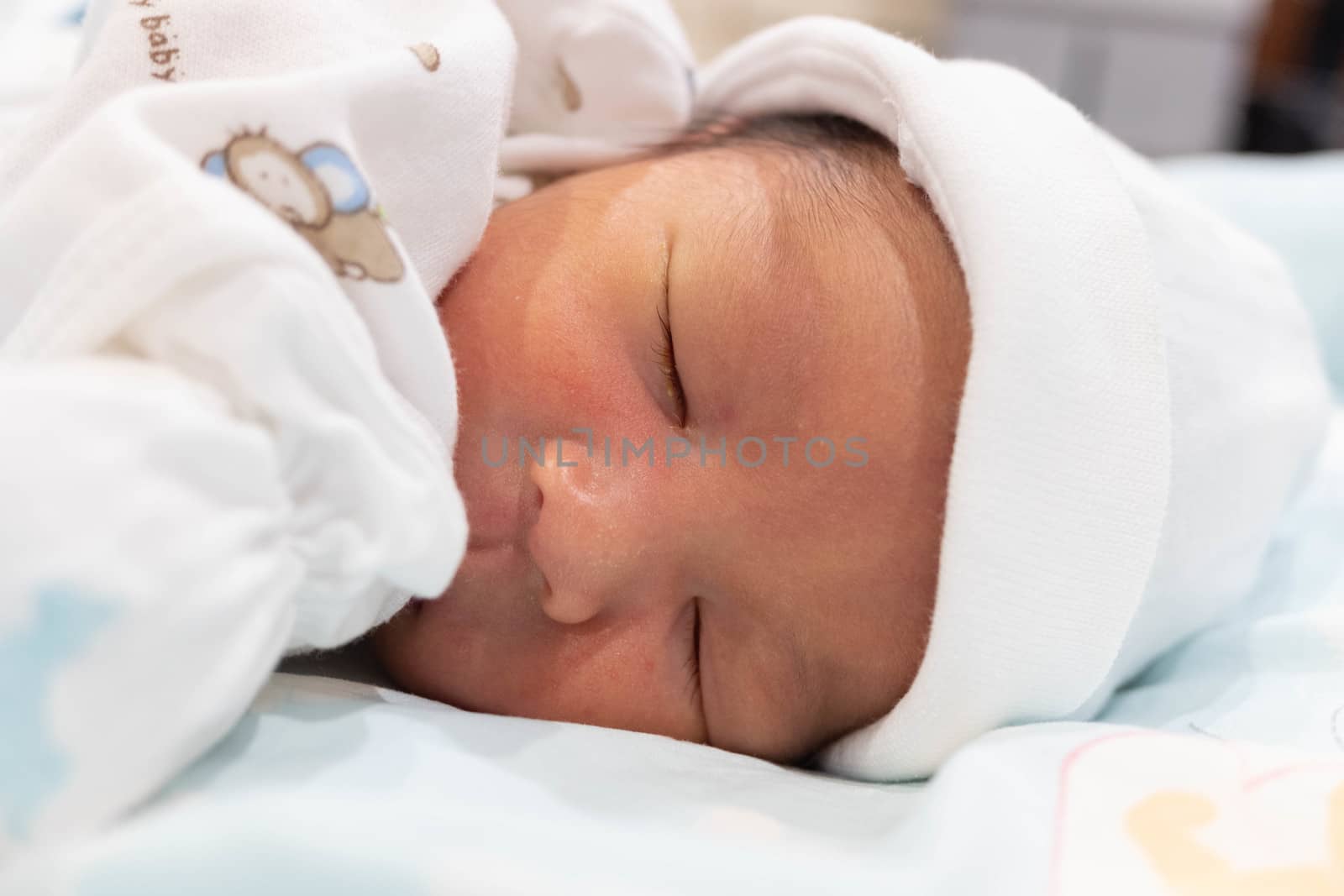 Sleeping cute New Born Baby infant with white baby cloth on the bed