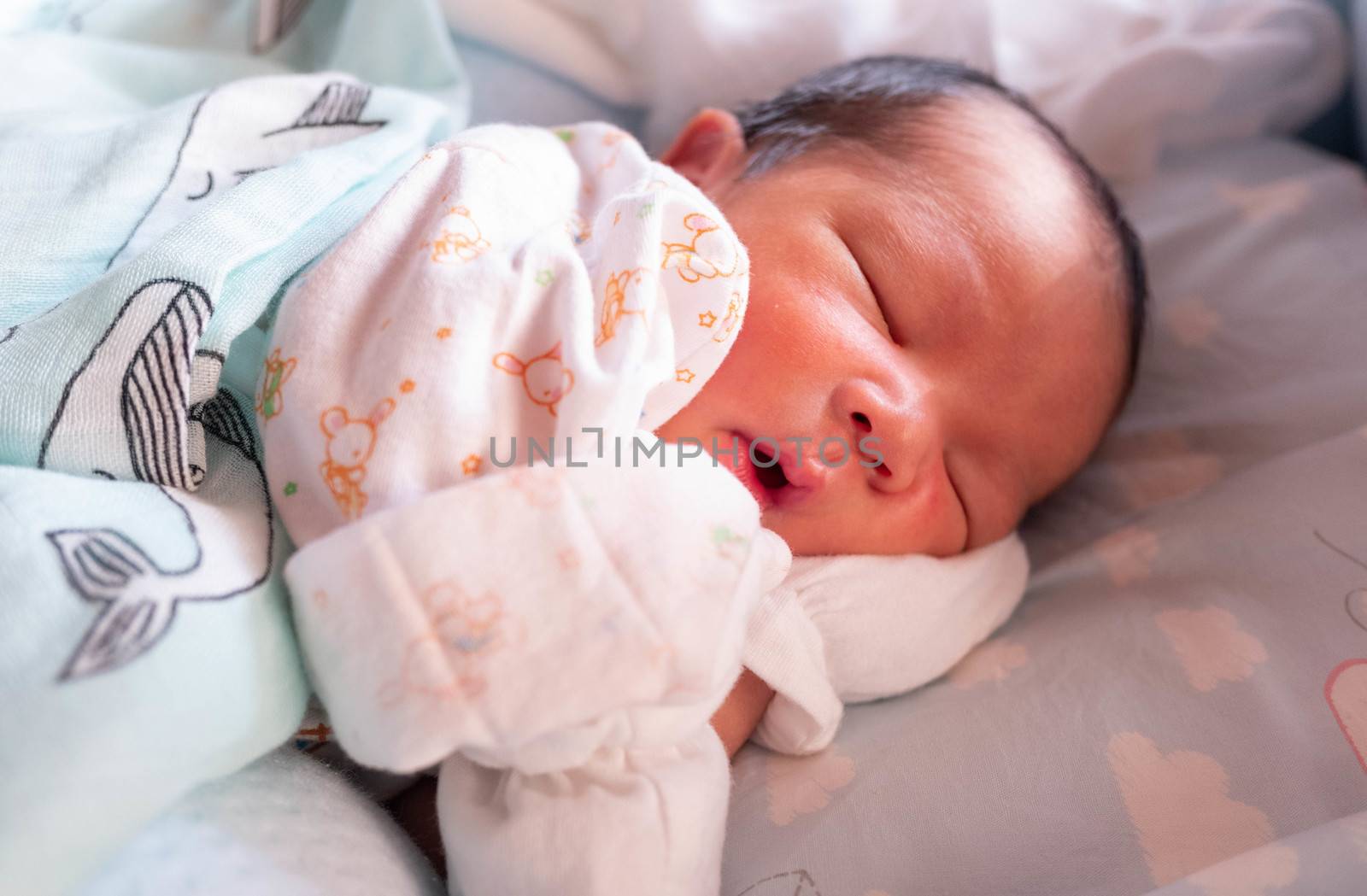 Sleeping cute New Born Baby infant with white baby cloth on the bed