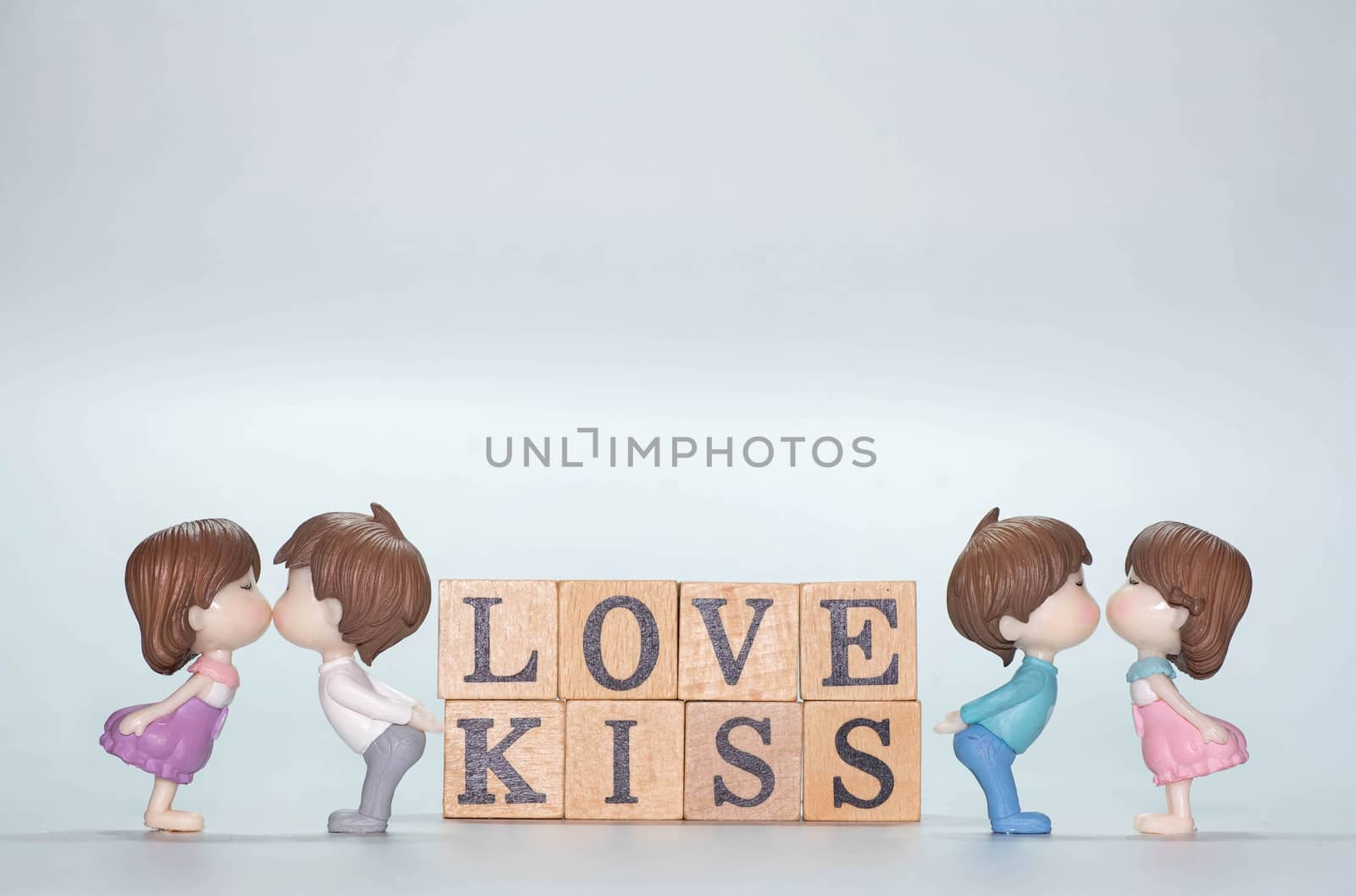 Miniature doll of couple boy and girl kiss and have Wooden alphabet word LOVE KISS isolate on White background